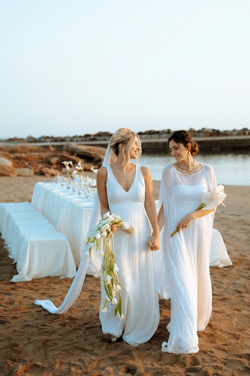 2 brides holding hands and walking holding bridal bouquets 