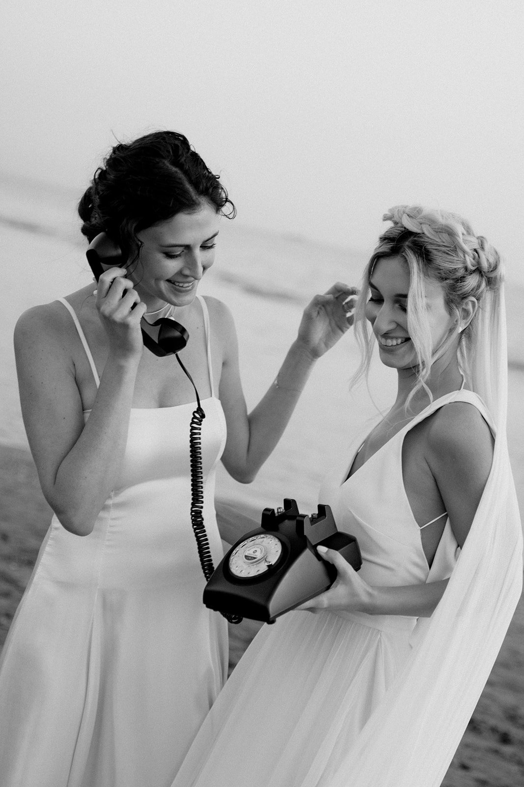 2 brides speaking on a vintage black phone 