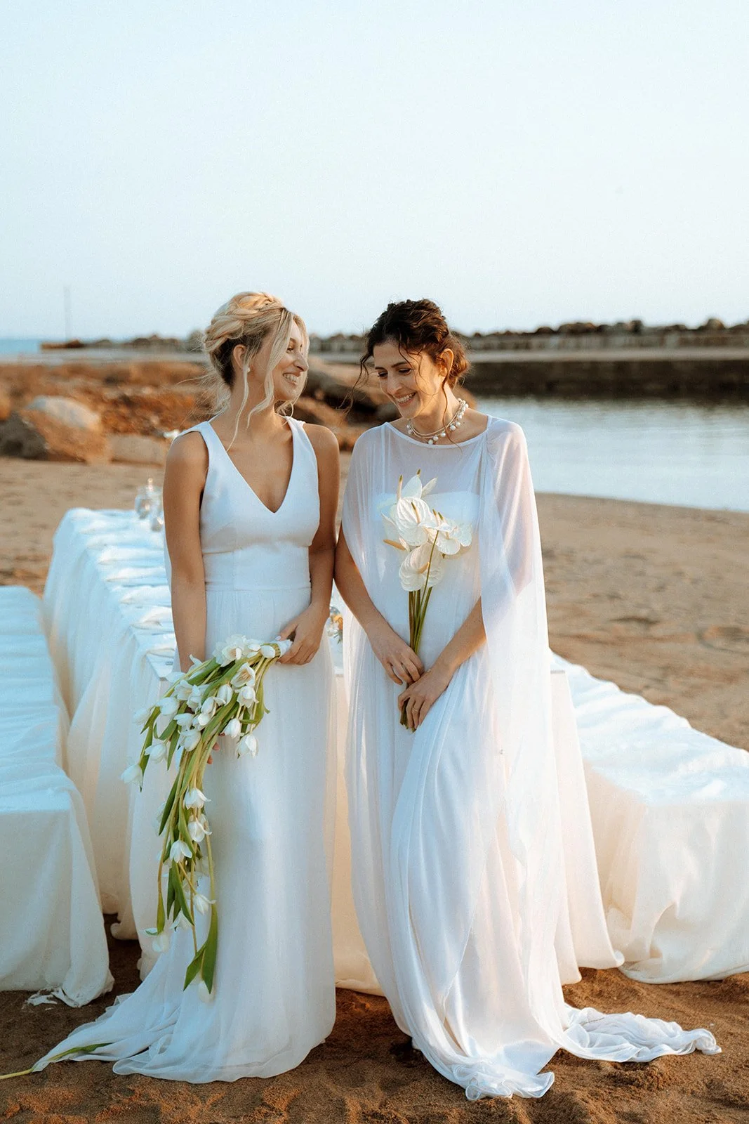 2 brides smiling holding a tulip and anthurium bouquets 