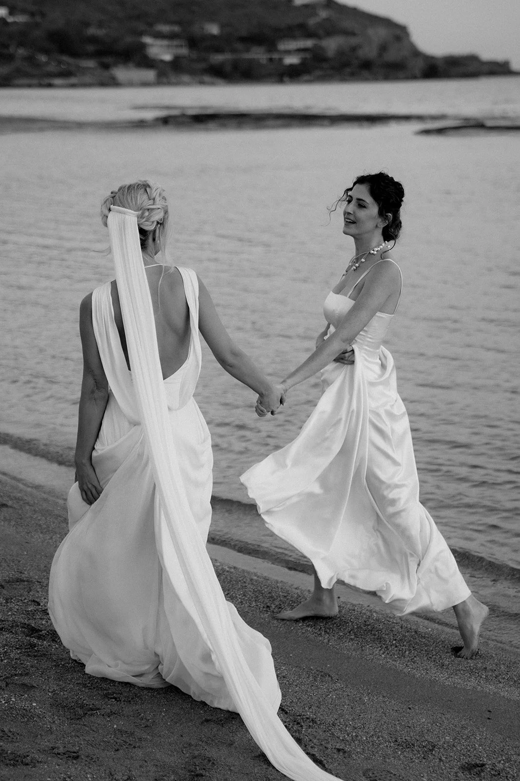 2 brides walking and talking next to the mediterranean sea 