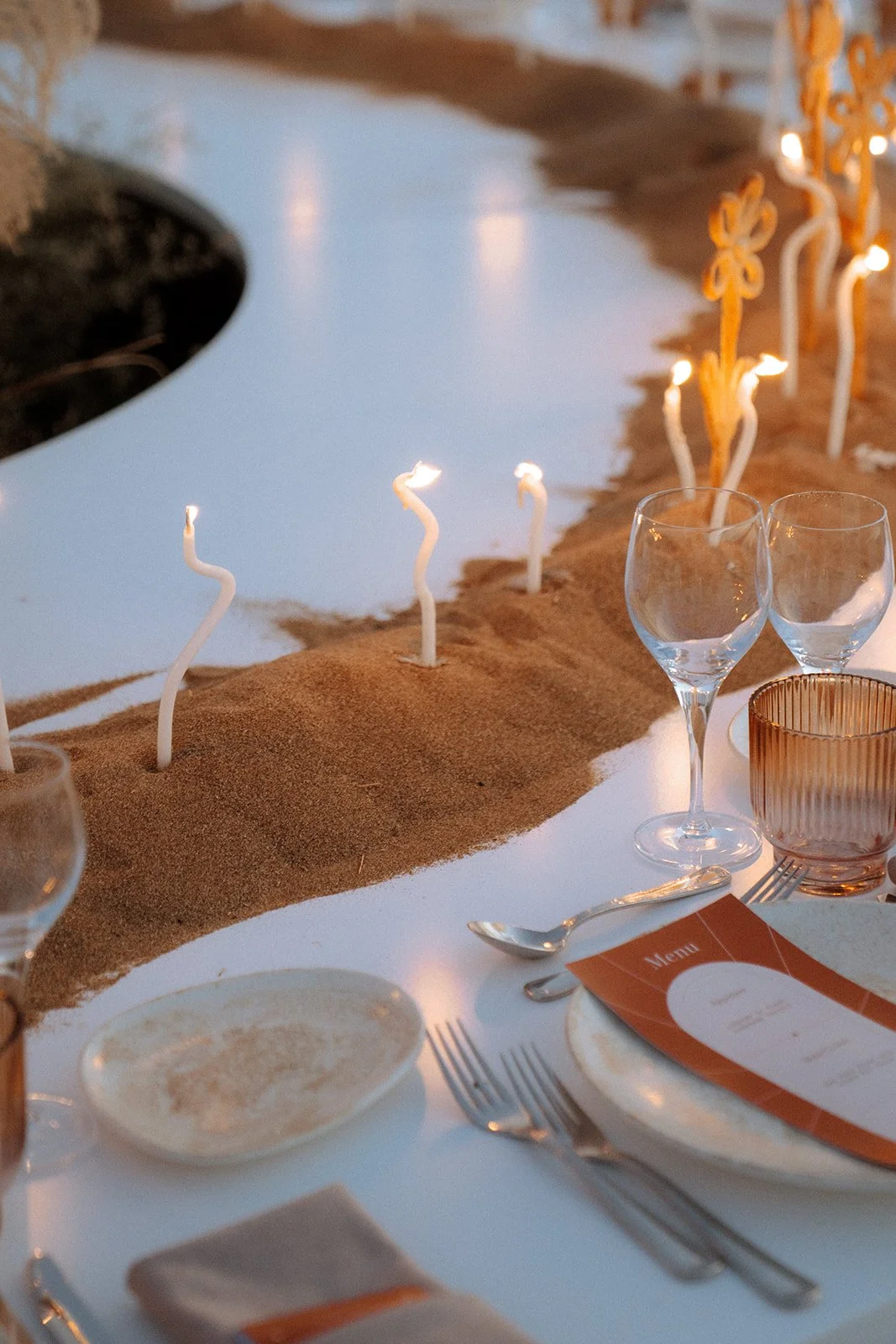 lit twisted taper candles in the sand wedding decor