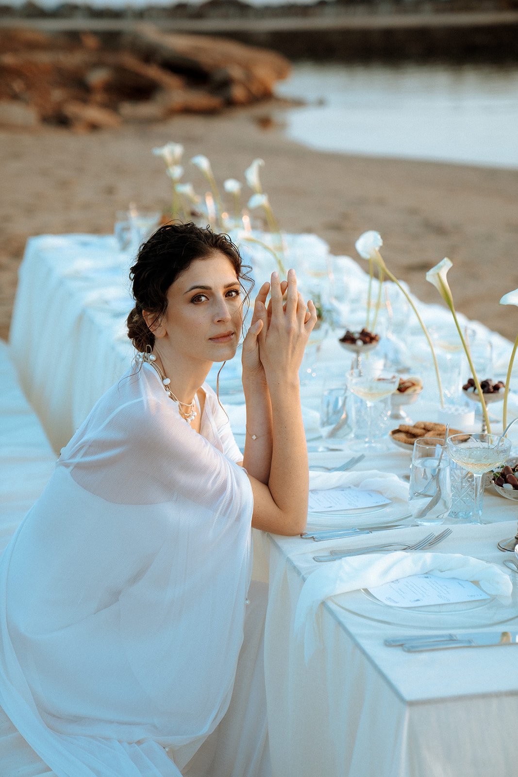 bride sitting on the wedding table with cala lilies 
