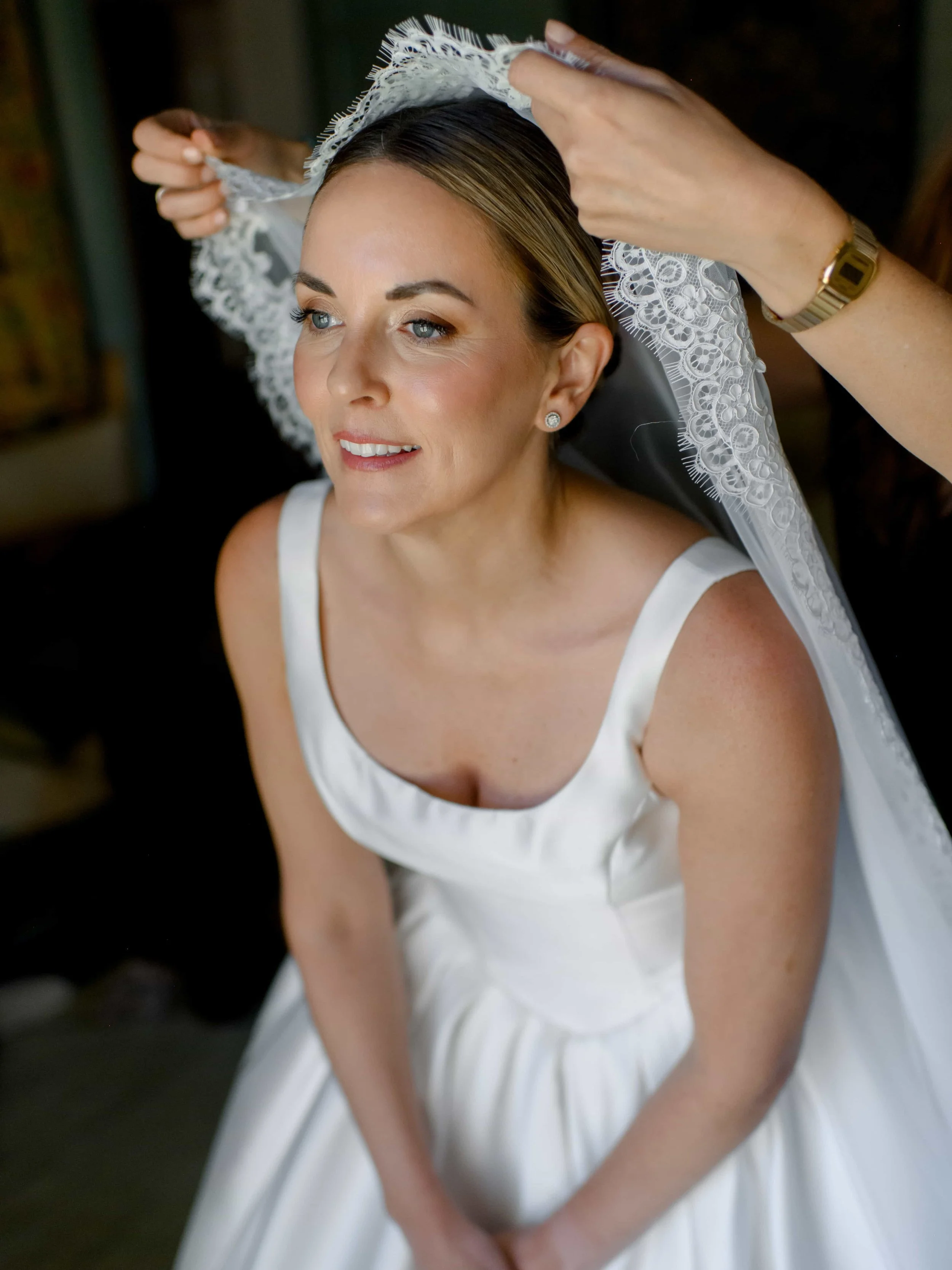 Hair stylist putting the veil on the bride