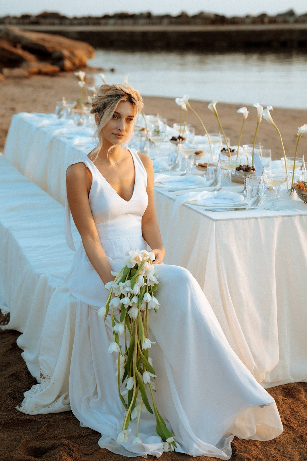bride sitting on the wedding table holding a white tulip contemporary bouquet 