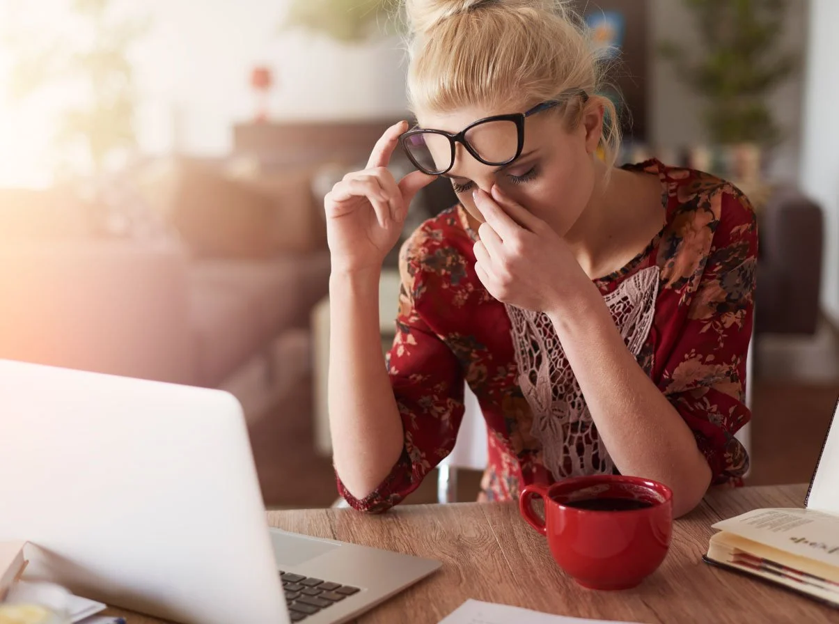 woman appears stressed at desk rubbing eyes