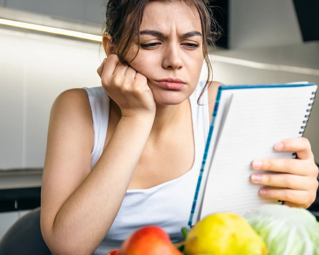 woman overwhelmed in kitchen reading more health notes