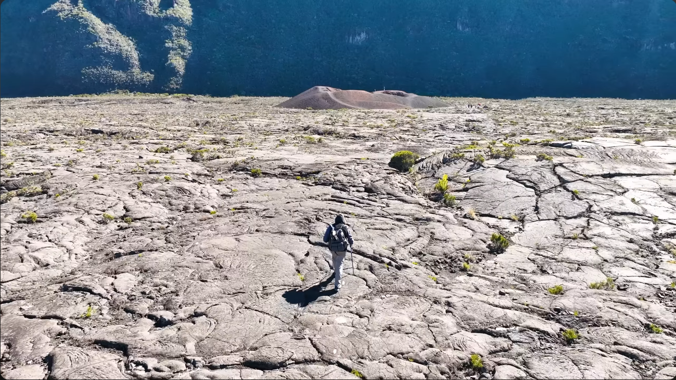 Hiker crossing hardened lava field toward Formica Leo crater on Piton de la Fournaise, Réunion Island