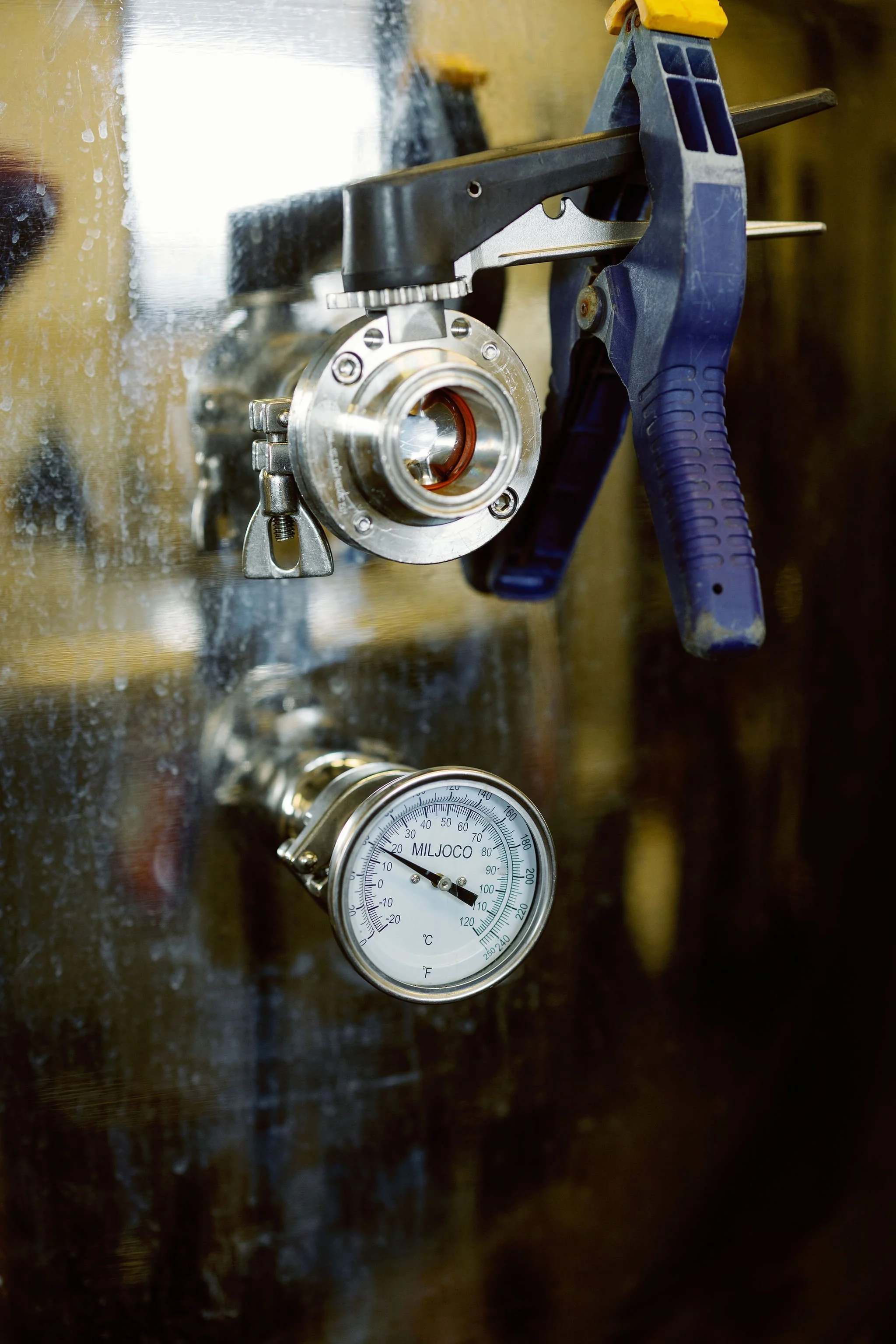 A close-up of a machine component mounted on a reflective surface with a clamp, and a thermometer showing 10°C.