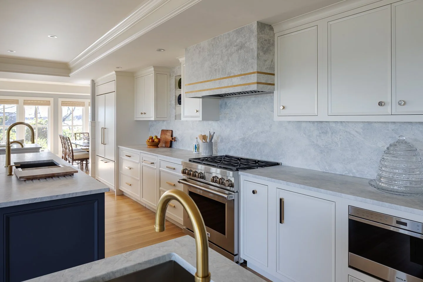 stone hood and full height backsplash white and navy cabinetry brass hardware