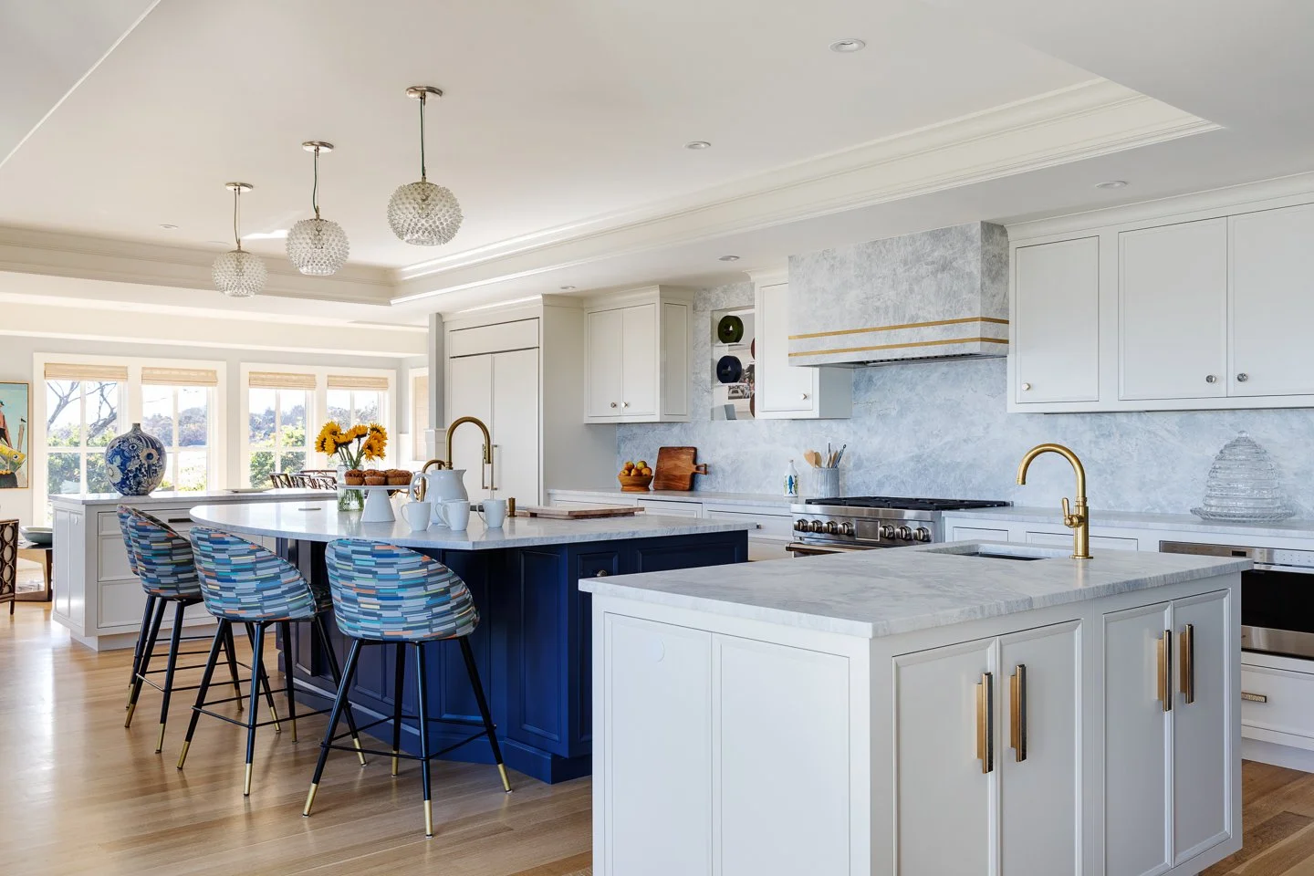white cabinetry with navy island and full height backsplash and stone hood