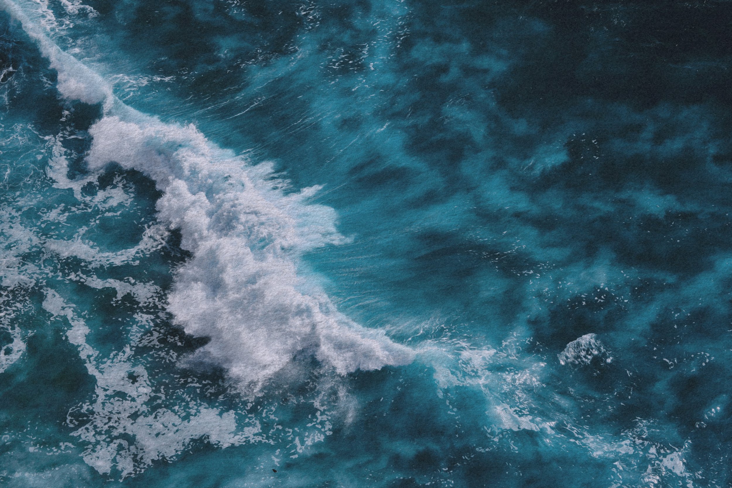 Aerial view of blue ocean water with white foam and waves.