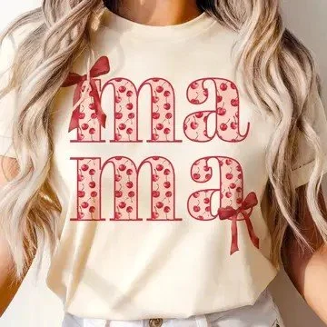 Close-up of a woman wearing a cream-colored t-shirt with the word 'Mama' repeated twice in pink, decorated with polka dots and a pink bow.