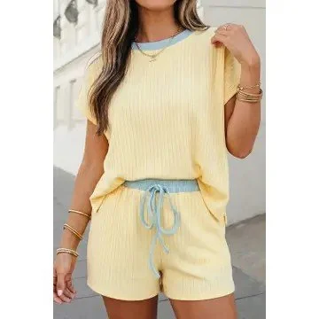 Woman wearing a yellow short-sleeve top and matching shorts with a blue drawstring, standing outdoors.