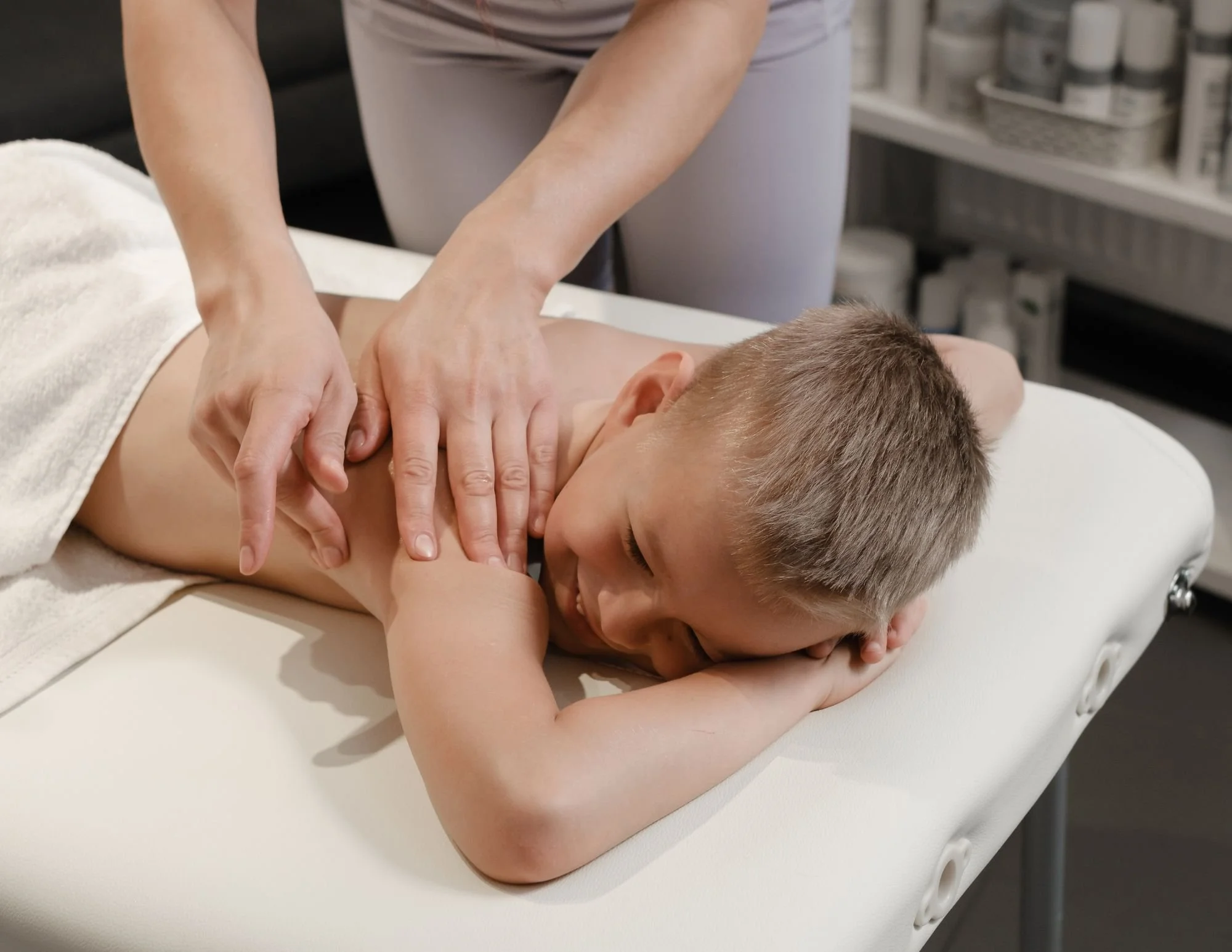 A child receives a massage on their back at a spa or massage therapy clinic.