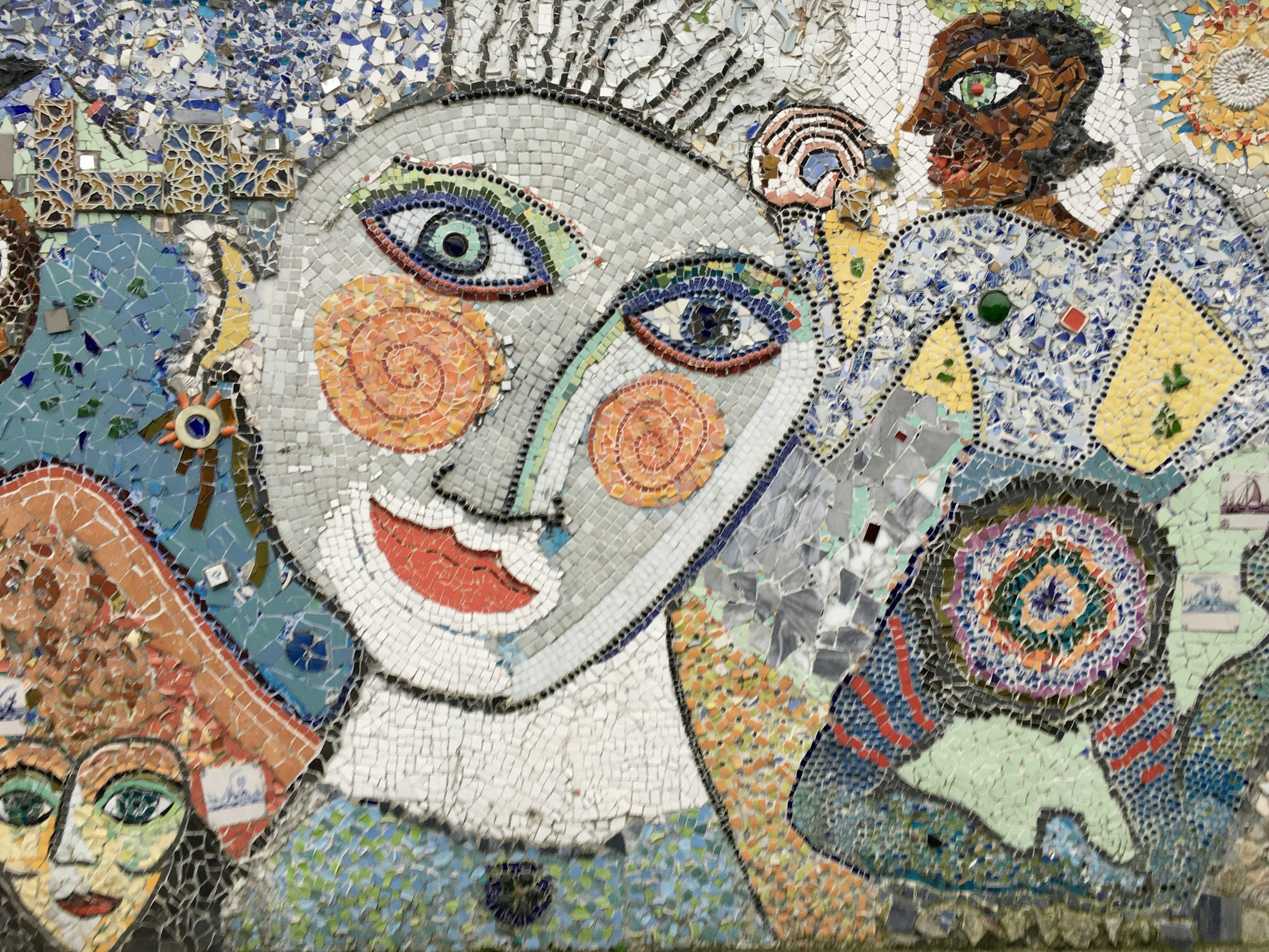 Colorful mosaic mural depicting a stylized image of a woman with cosmic elements, an astronaut, and various abstract designs.