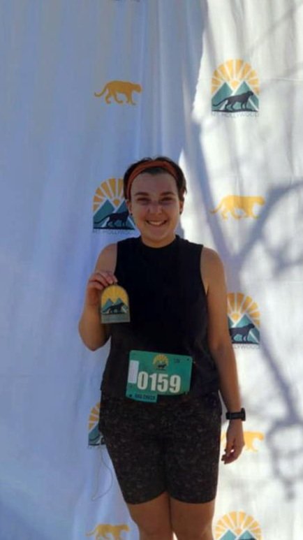 Runner holding a medal after finishing an endurance race, representing coaching success.
