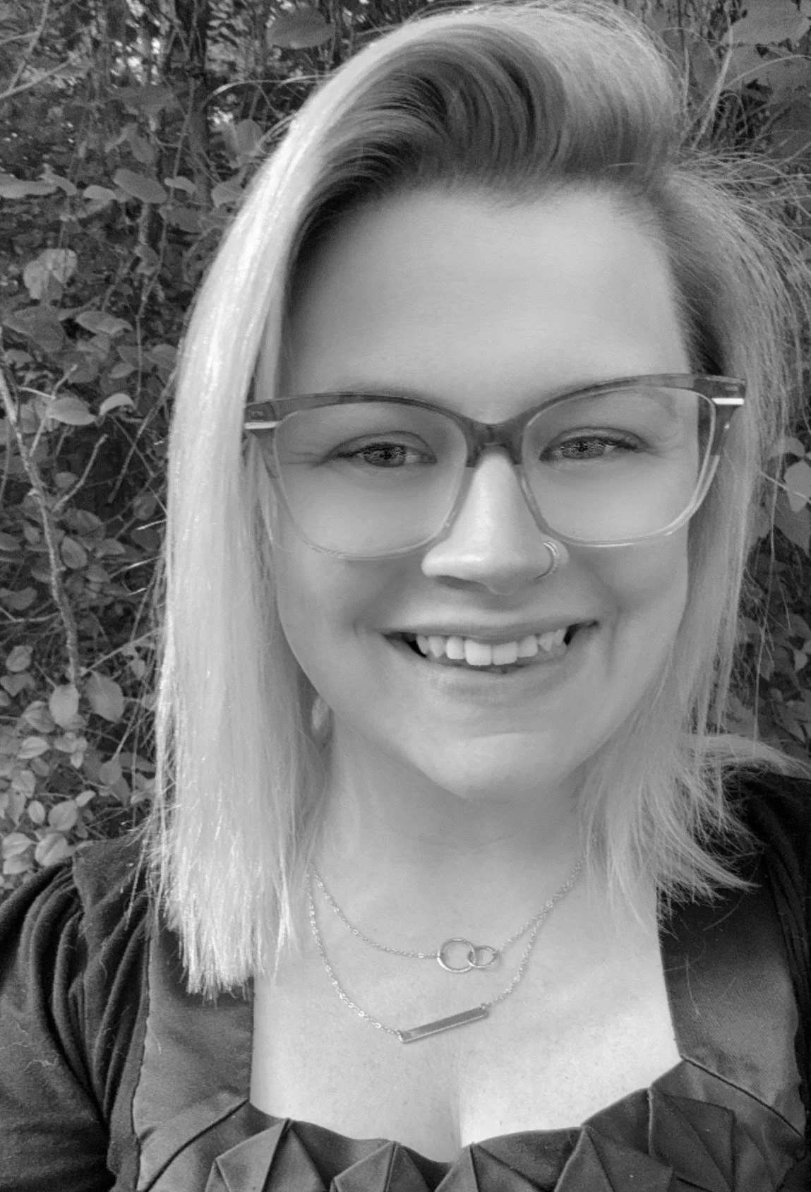 Samantha Anderson, associate at Ascend Group, smiling with straight light hair and glasses, wearing layered necklaces outdoors.