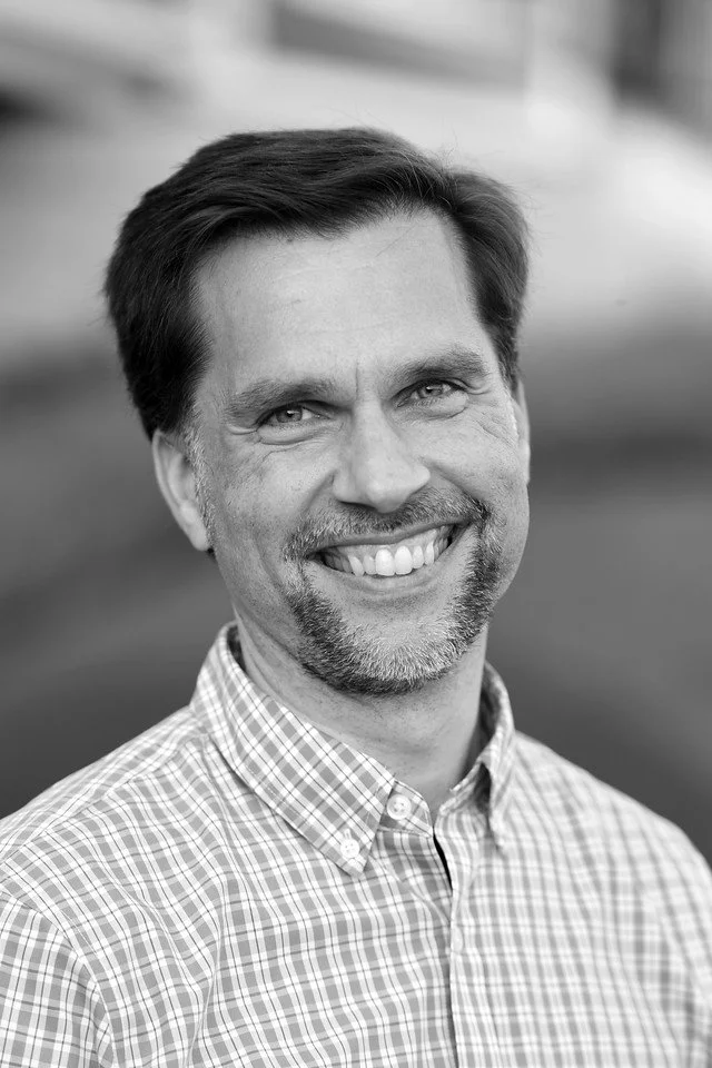 Tim George, Director at Ascend Group, smiling in a plaid shirt, facing camera outdoors