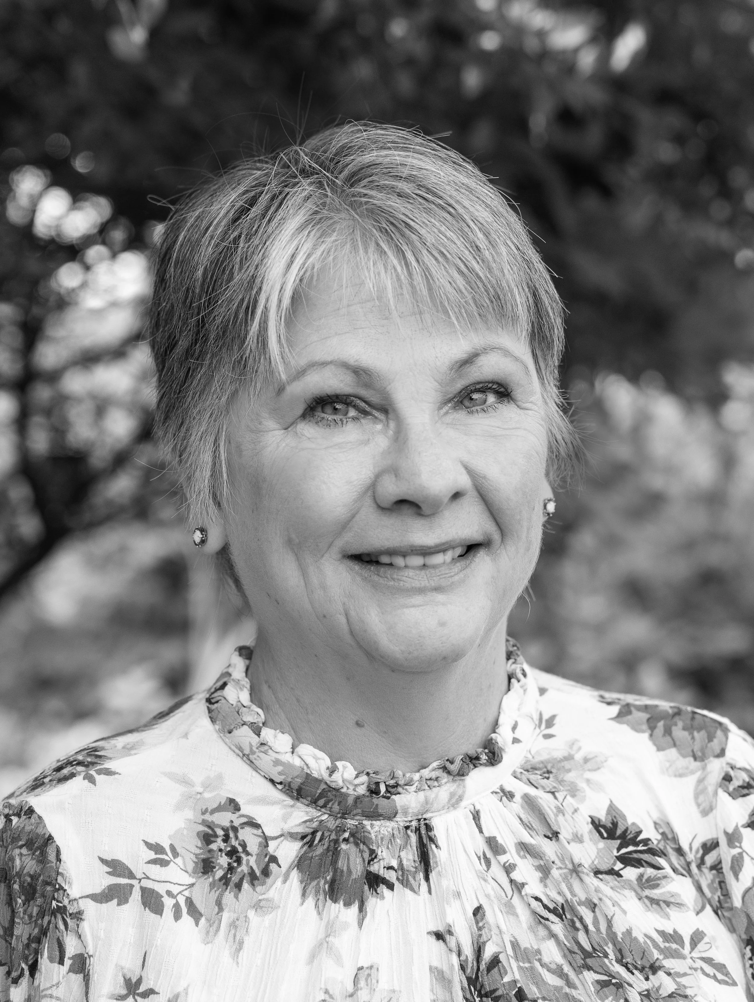 Cheryl Lynn, associate at Ascend Group, with short light hair, wearing a floral blouse, photographed outdoors.