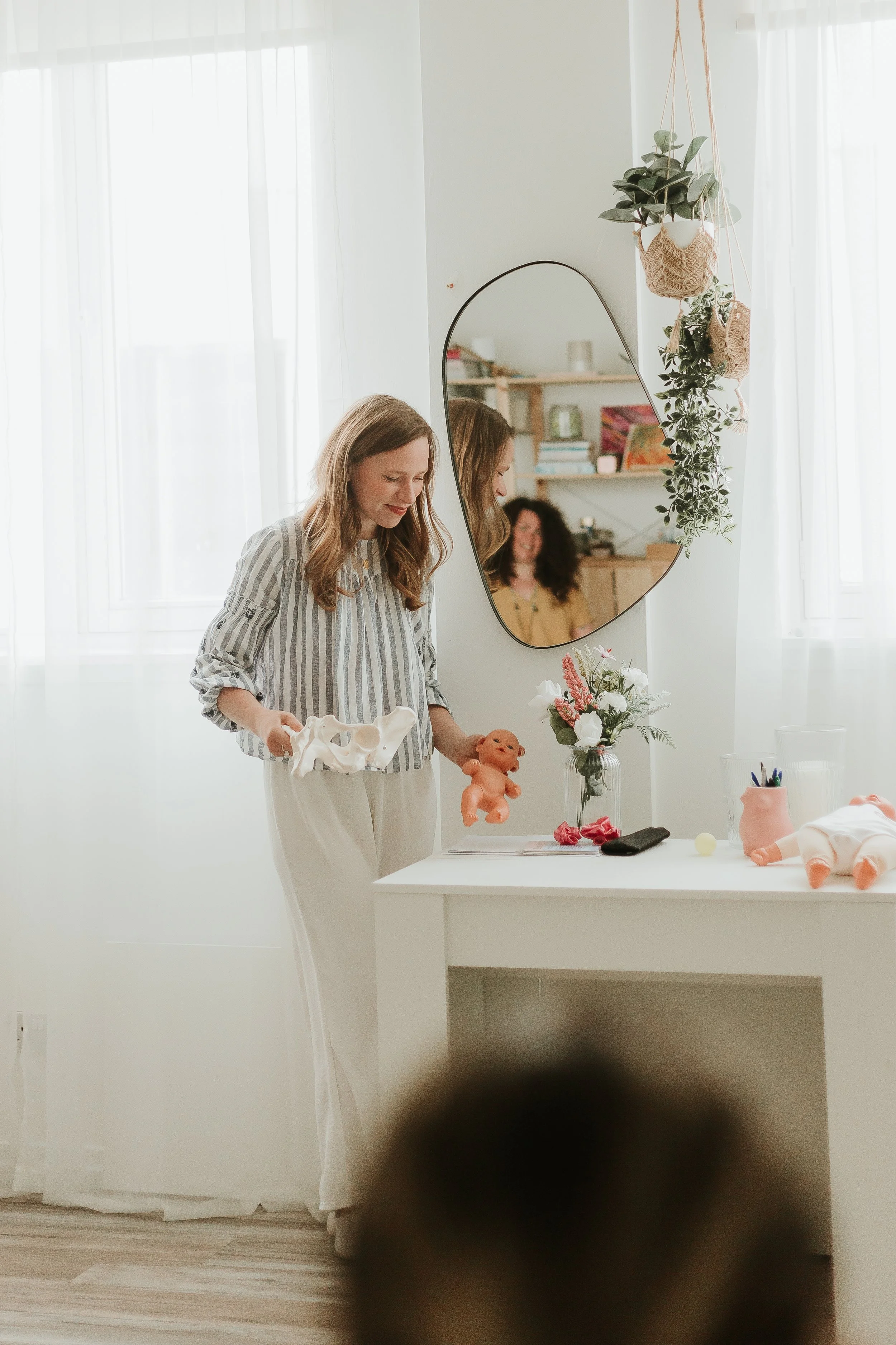 Aurelija - antenatal and hypnobirthing teacher standing next to a table with baby dolls and a flower vase.