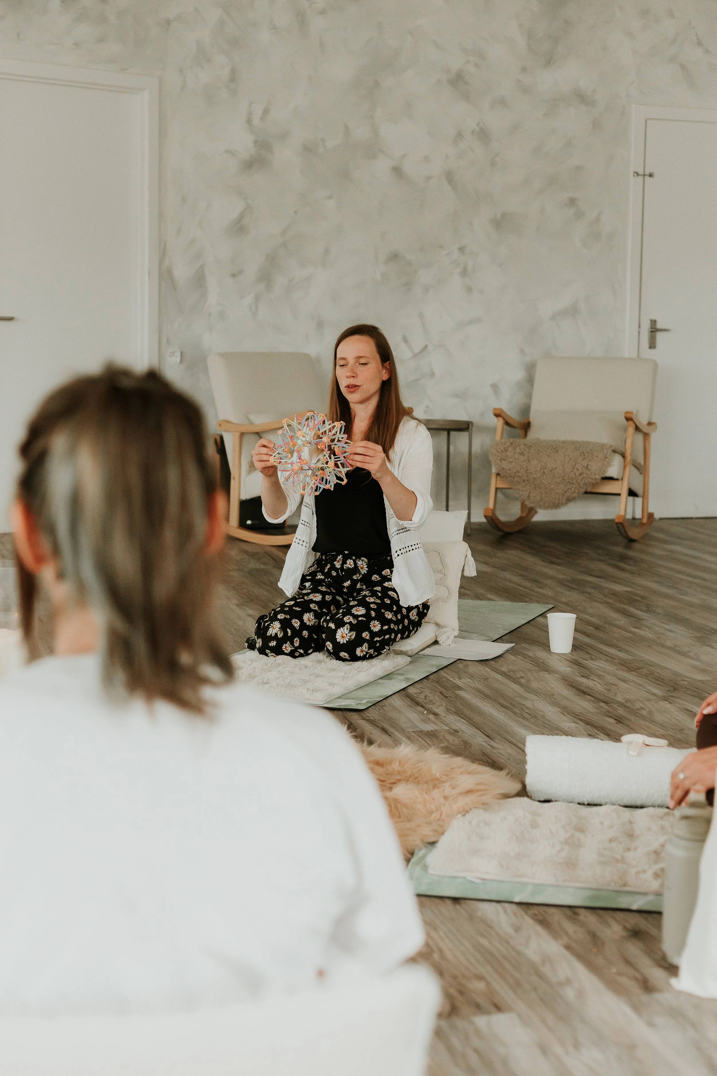 Aurelija demonstrating a breathing exercises for labour to a room full of pregnant women. Kneeling on the floor and holding an expanding ball.
