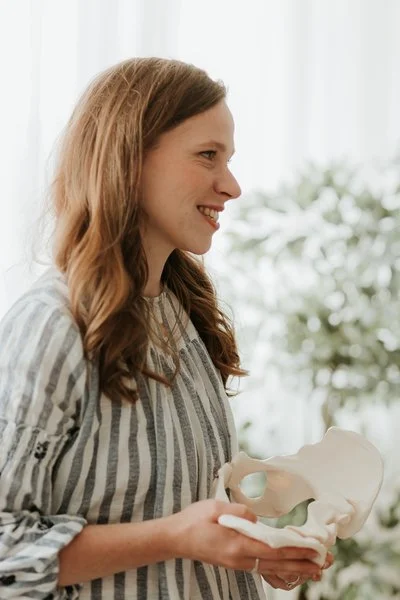 Aurelija smiling and holding a pelvic bone model.