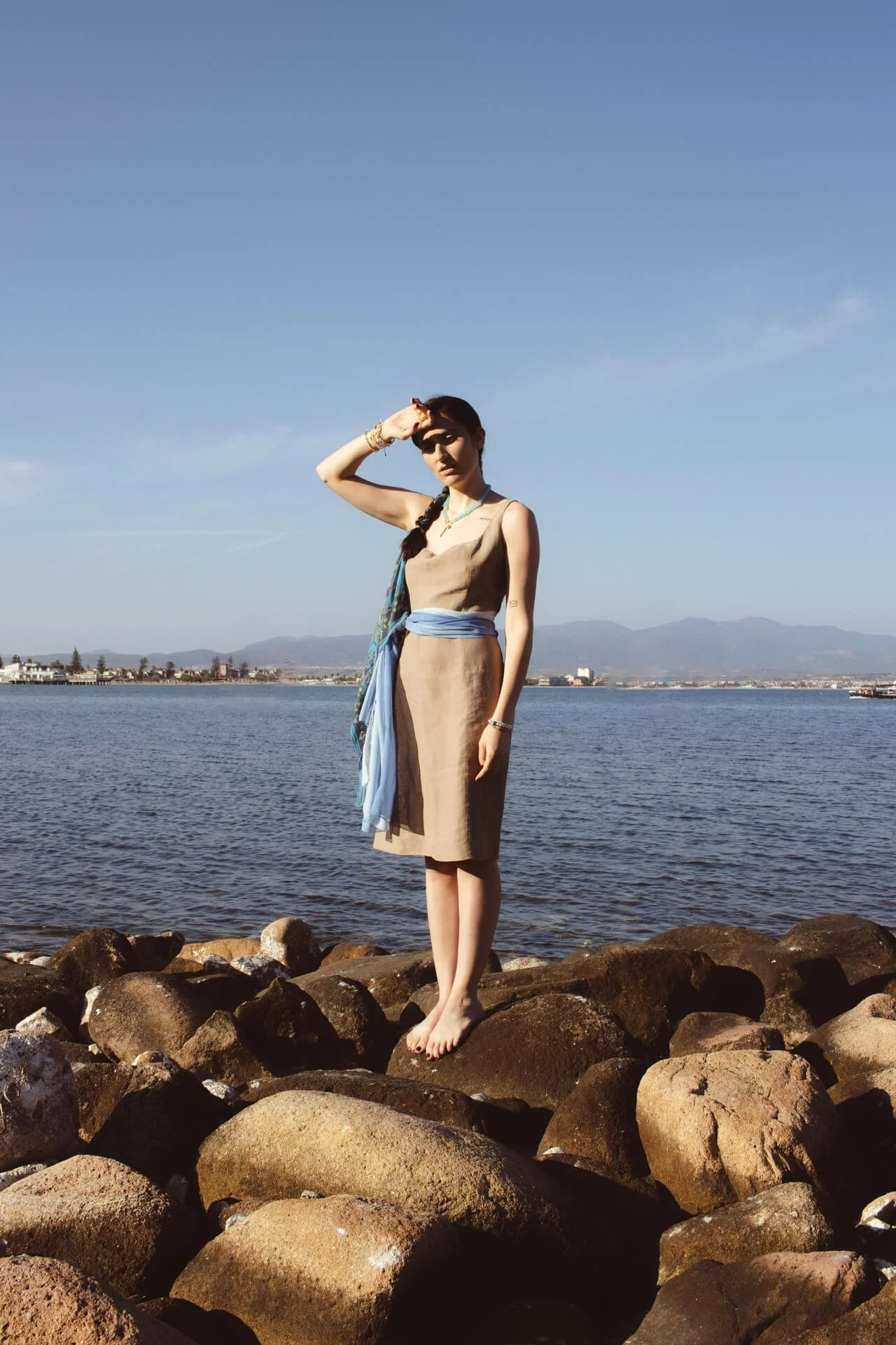 Figura intera di ragazza sugli scogli al tramonto