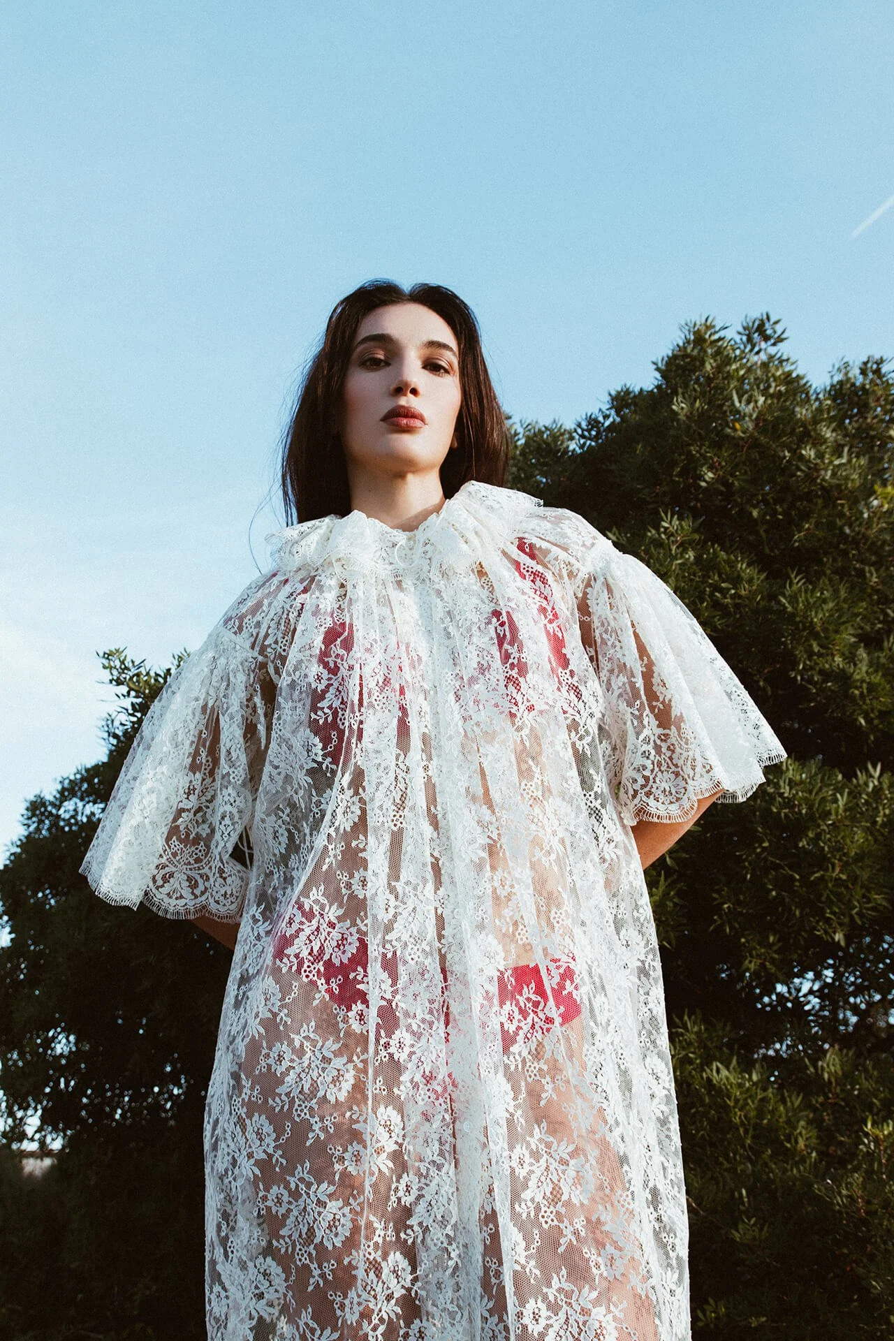 Modella con i capelli scuri con un vestito bianco ricamato