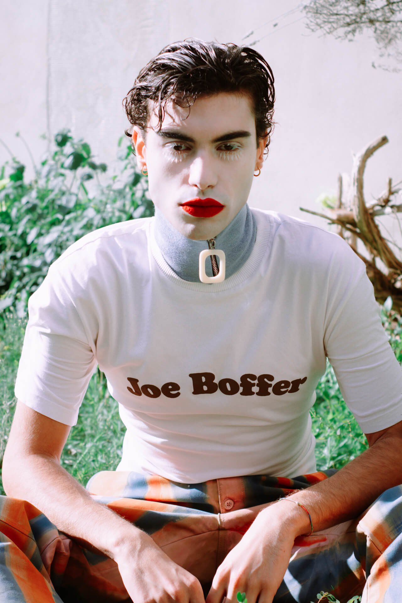 Ritratto di ragazzo in un giardino con piante con T-shirt con scritta Joe Boffer - NATURALLY SWEET