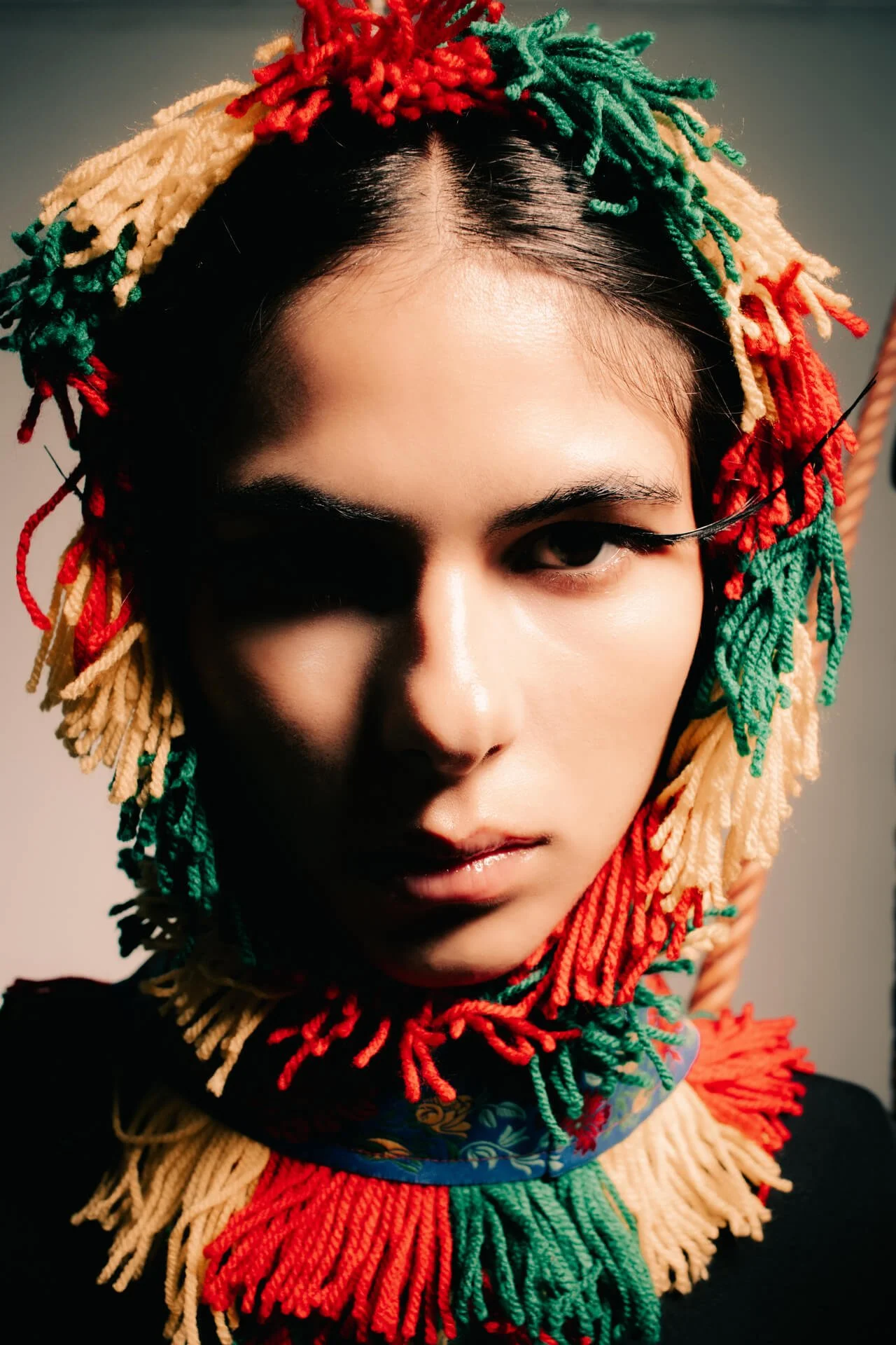 Primo piano di una ragazza mora con i capelli lunghi che guarda in camera, foto iin studio a colori