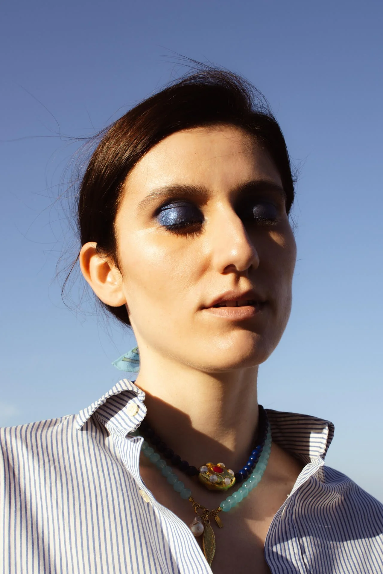 Primo piano di ragazza mora con gli occhi truccati di blu scuro al tramonto