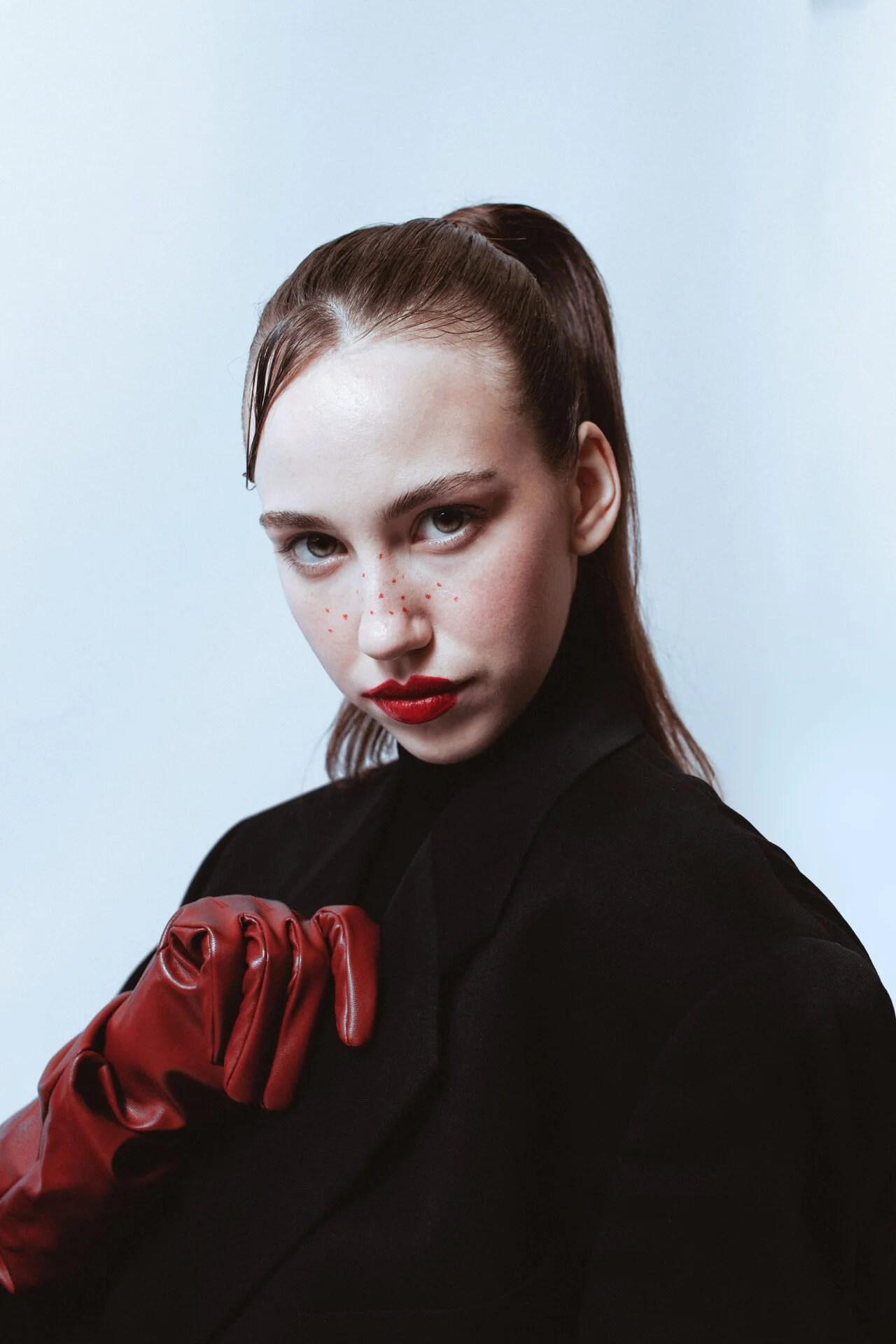 Ritratto editoriale di ragazza bionda con giacca nera e collo alto e rossetto rosso