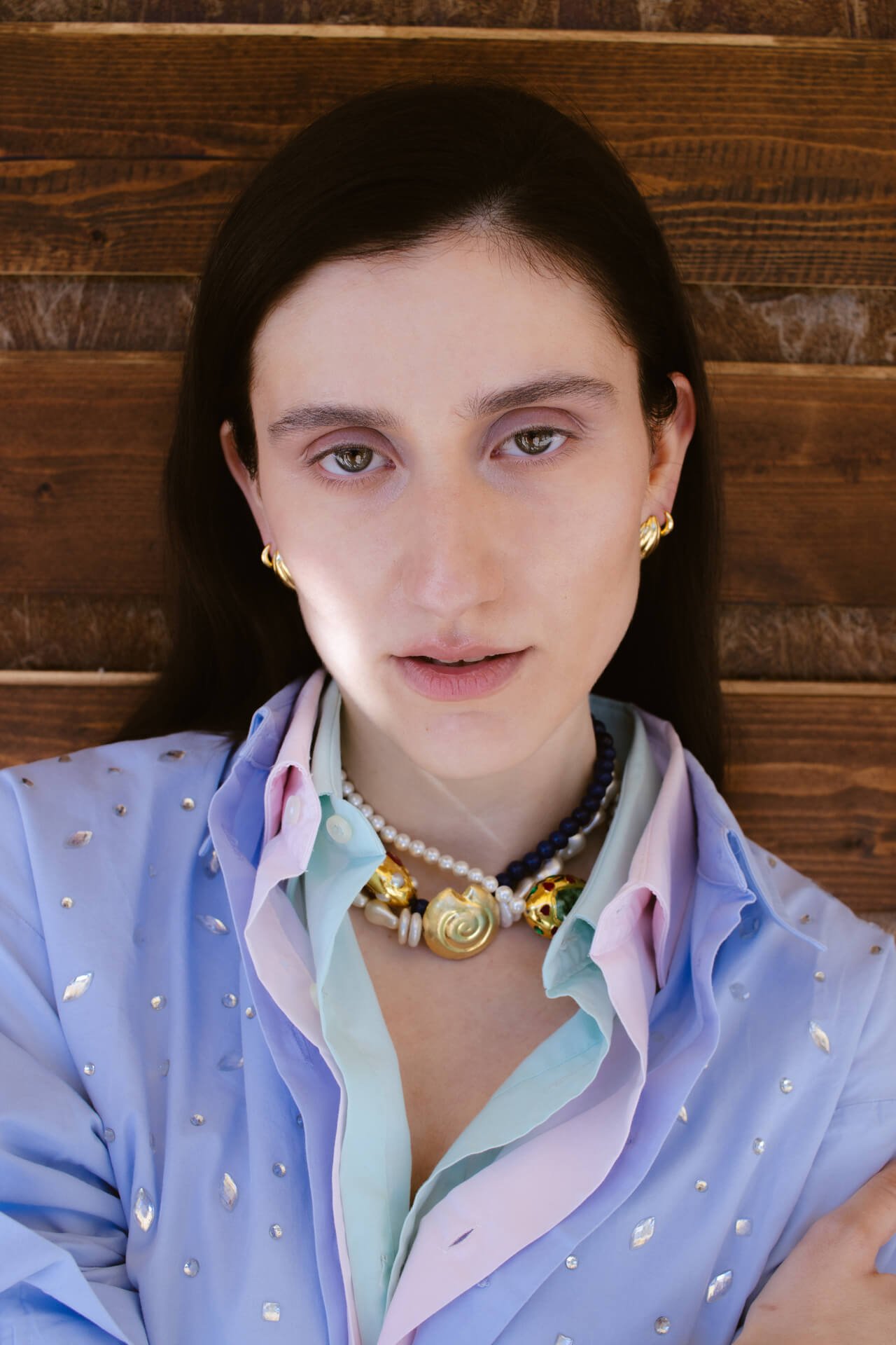 Primo piamo di ragazza mora che indossa delle camicie e dei gioielli