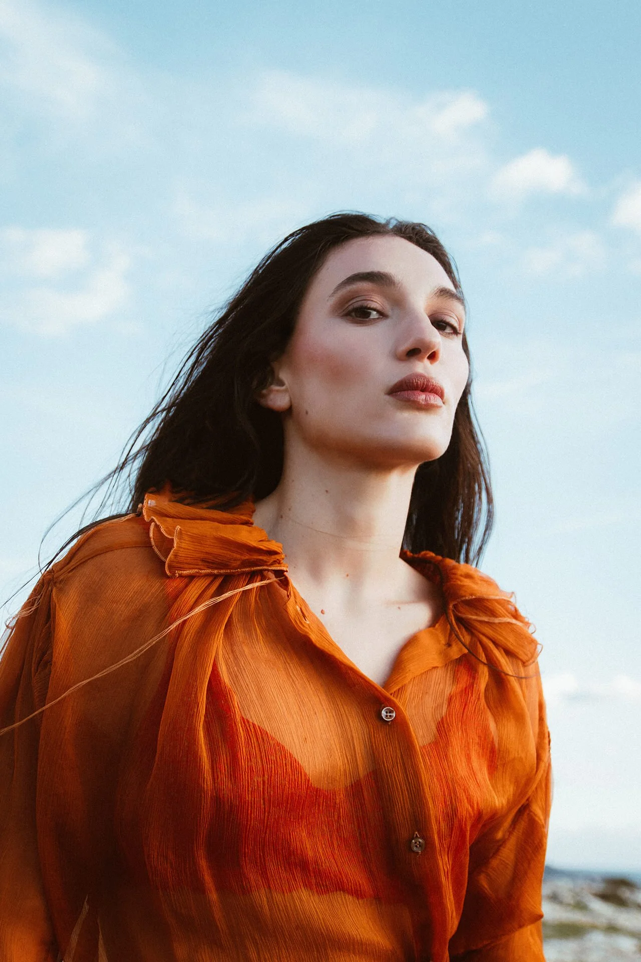 Modella con i capelli scuri lisci con una camicia arancione