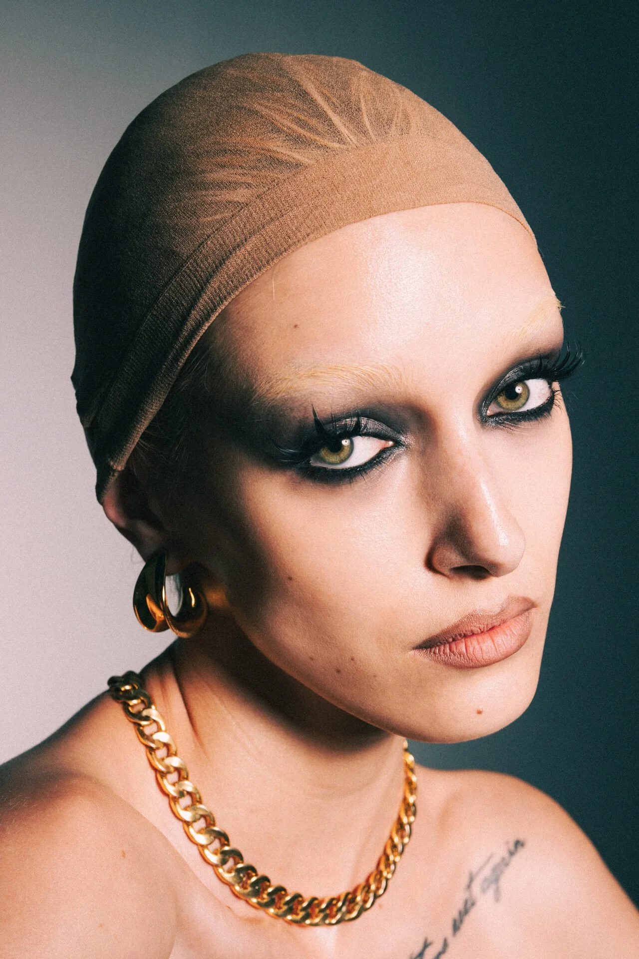 Primo piano di ragazza con trucco intenso e capelli raccolti.