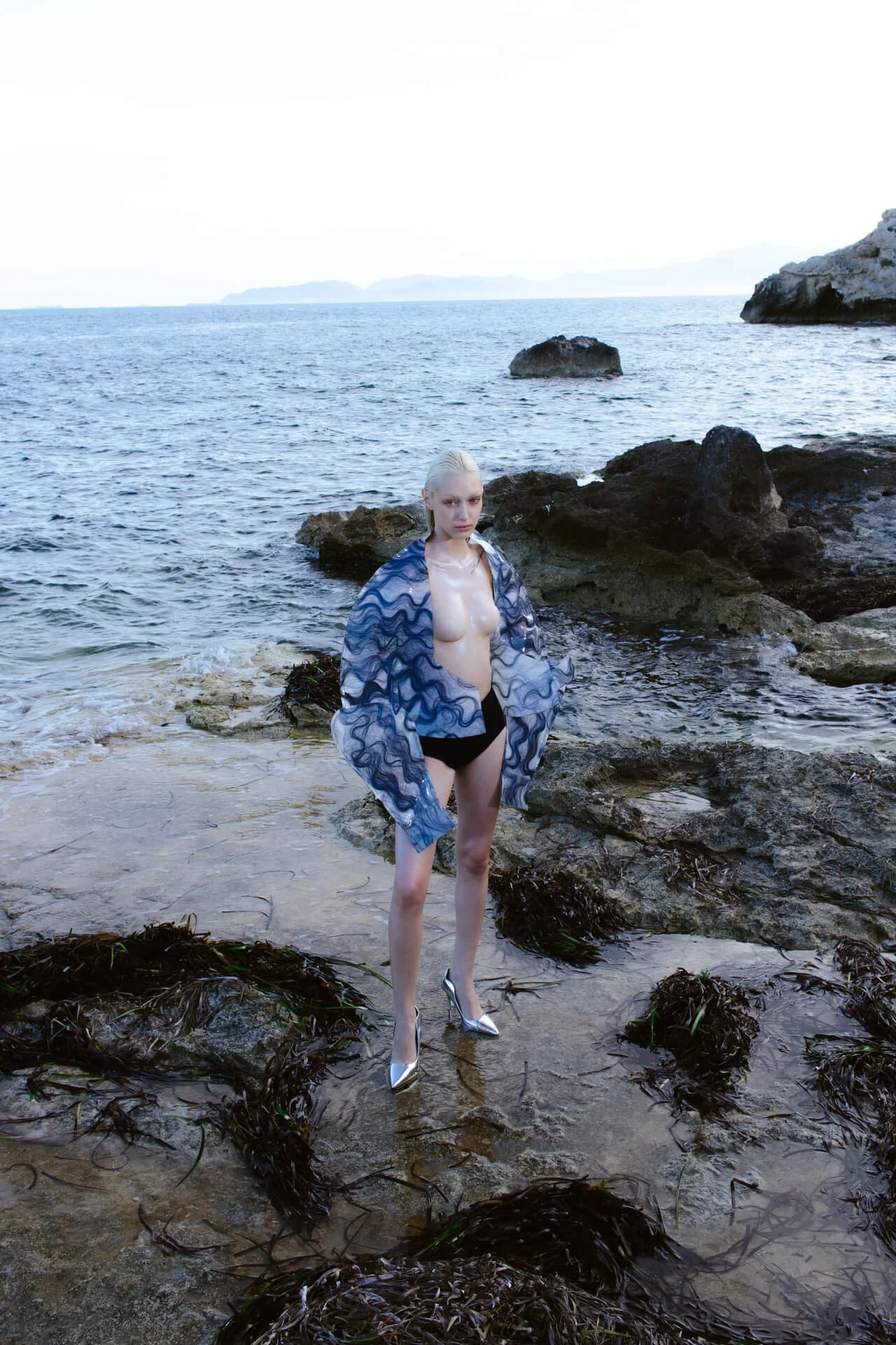 Landscape picture of a woman standing in the middle of the sea shore
