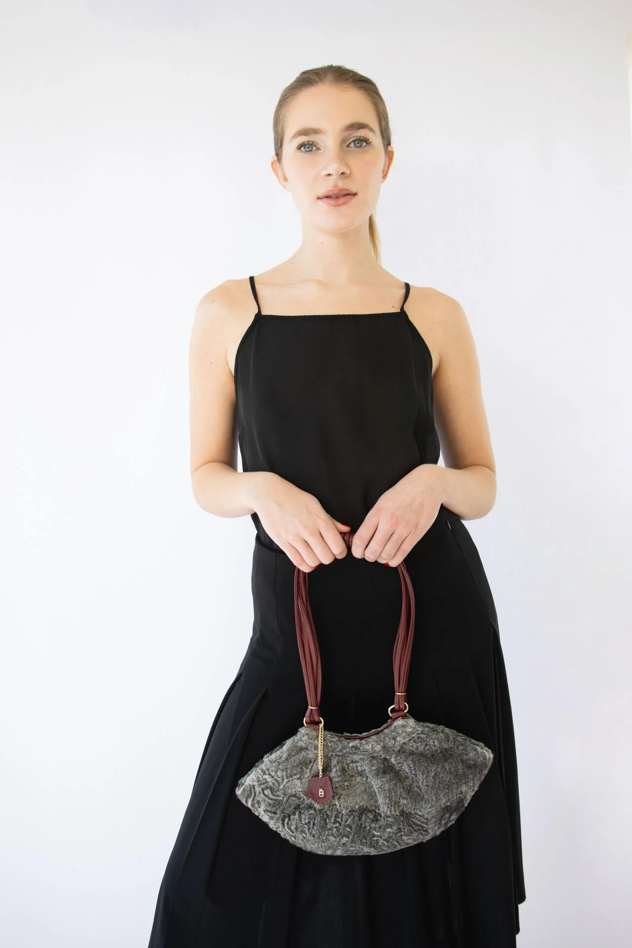 Ritratto editoriale di ragazza bionda con vestito nero e una borsa Bistrusso