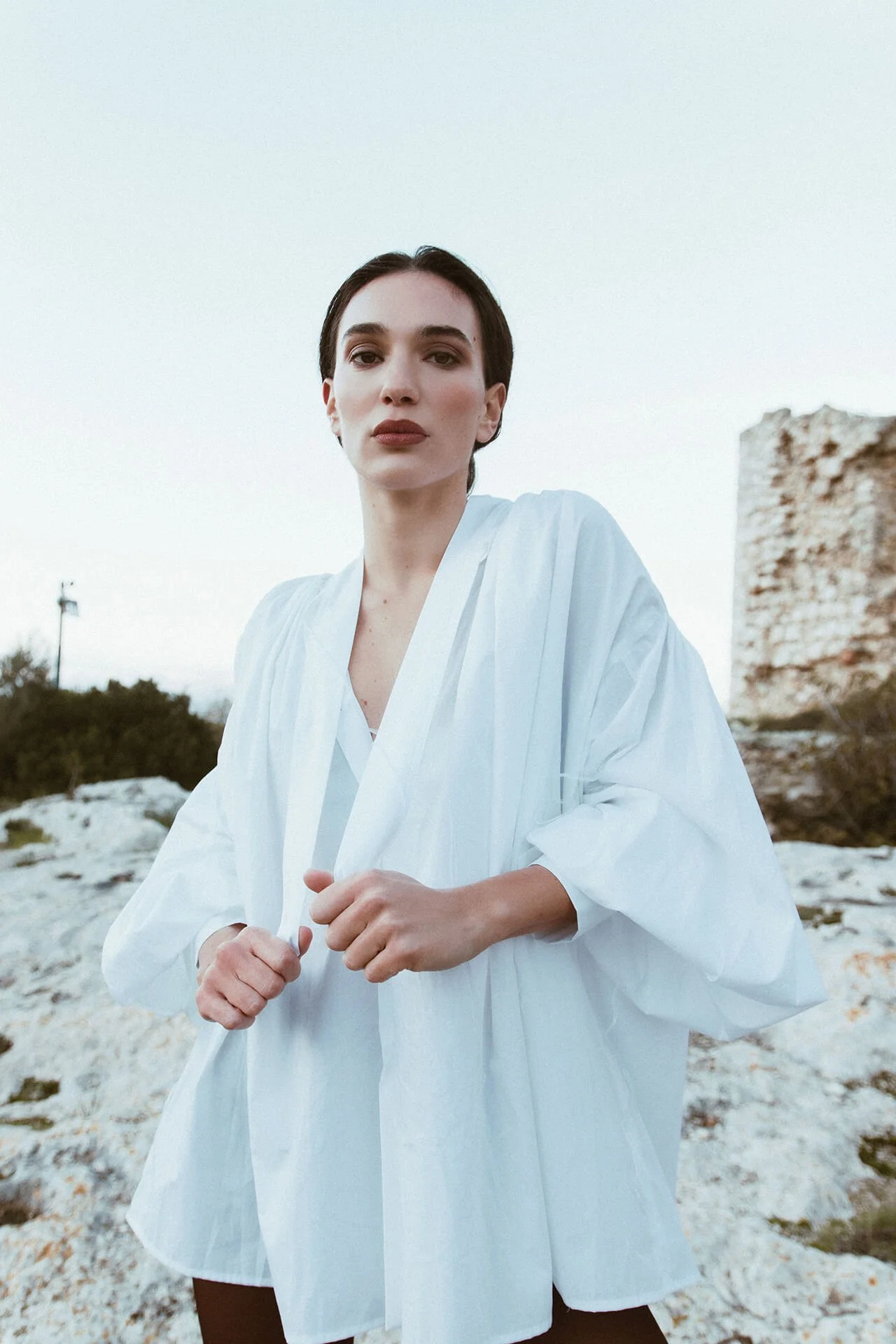Modella con i capelli scuri raccolti con una camicia bianca