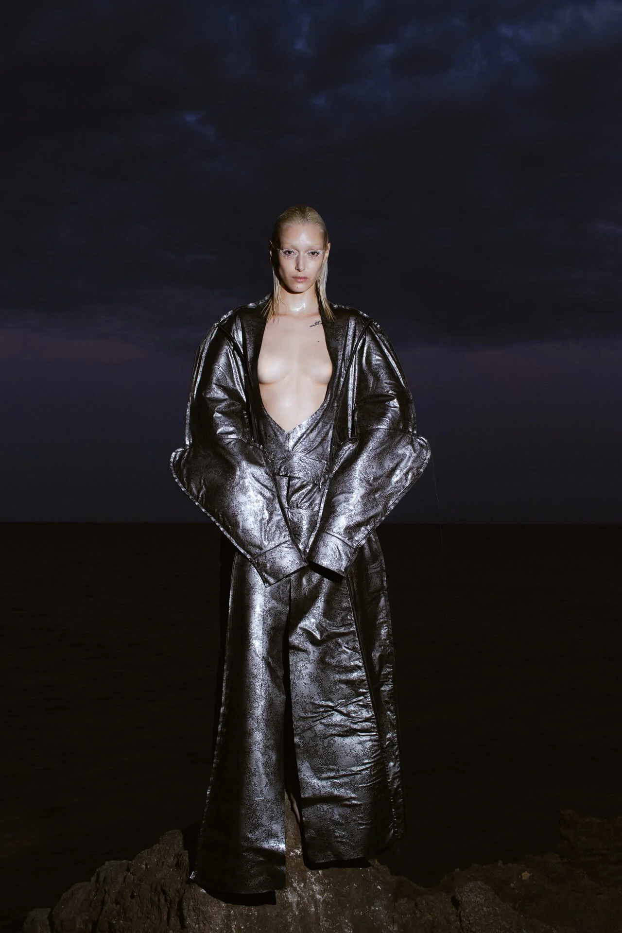 Full shot of a woman standing in the middle of the sea shore at night