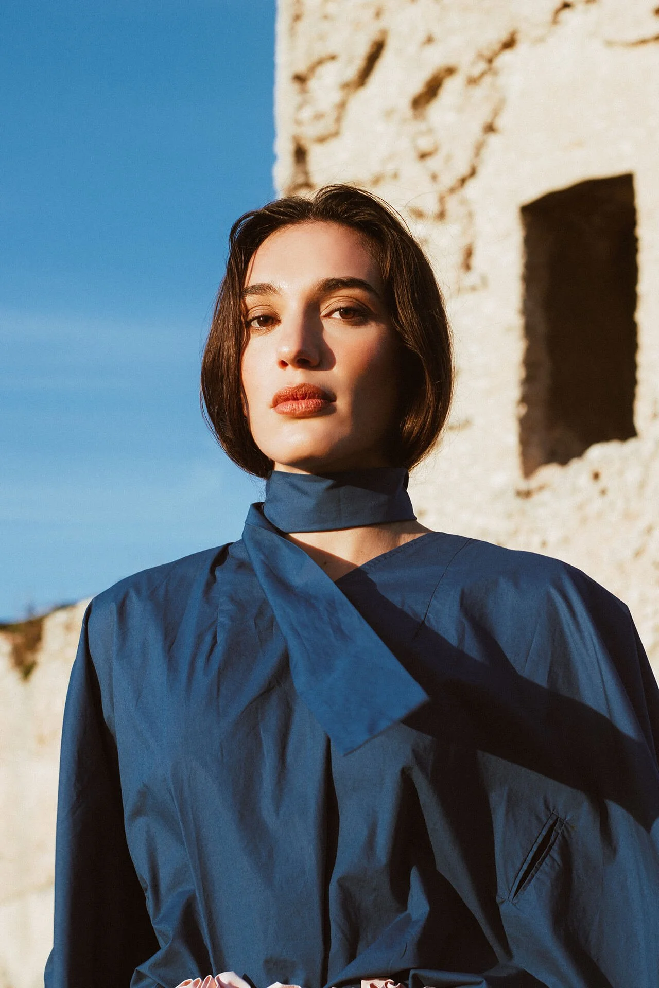 Ritratto editoriale di ragazza mora con camicia e foulard blu.