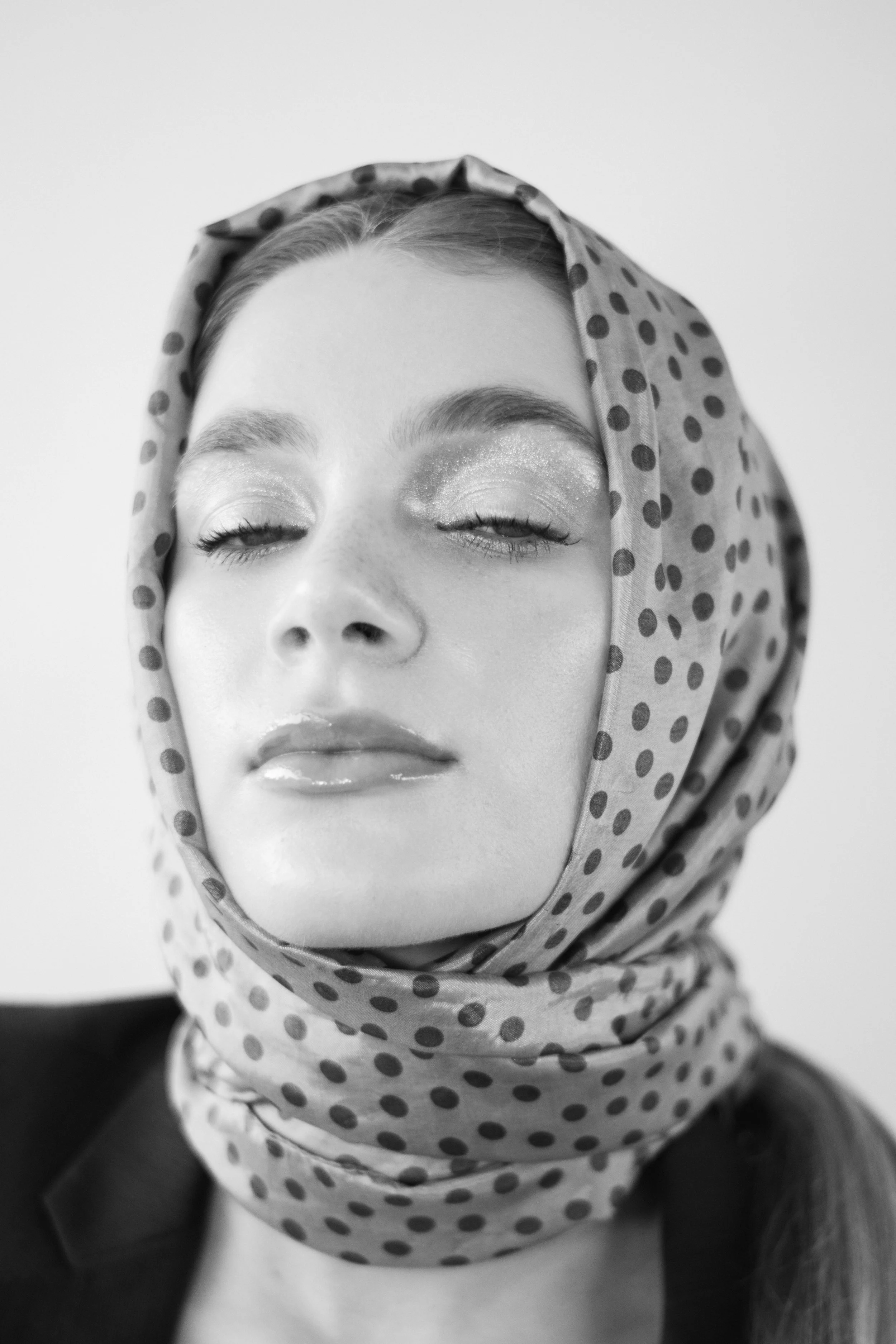 Ritratto editoriale di ragazza bionda con giacca nera e foulard.