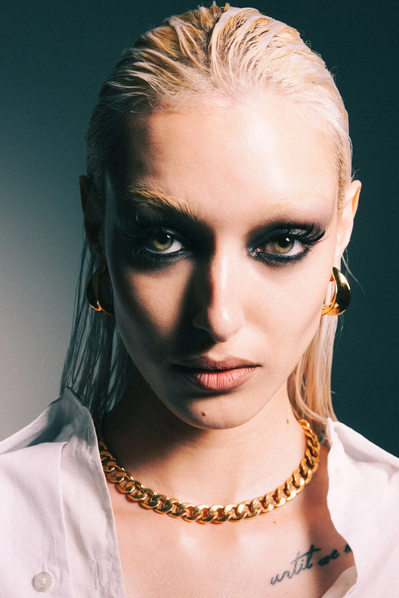 Primo piano di ragazza con trucco intenso e capelli raccolti con giochi di luci e ombre.