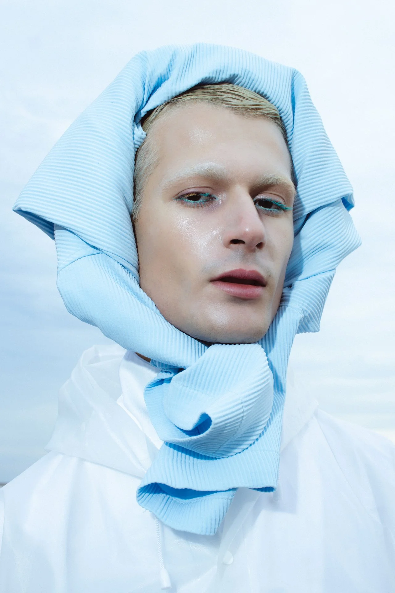 Portrait of a blonde young man wearing a blue shirt as a headpiece