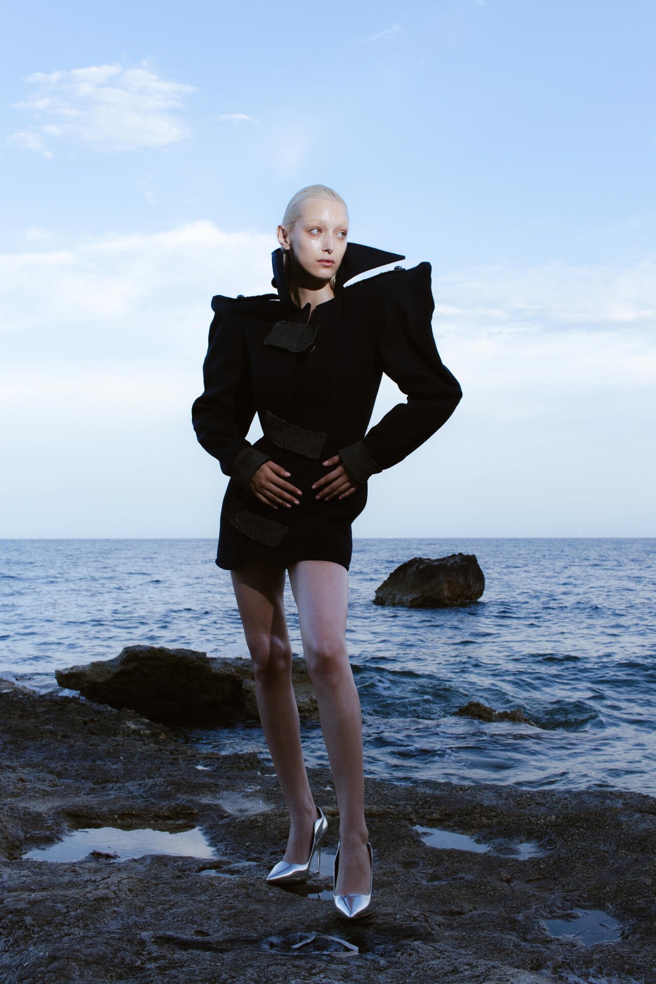 Full shot of a woman standing in the middle of the sea shore
