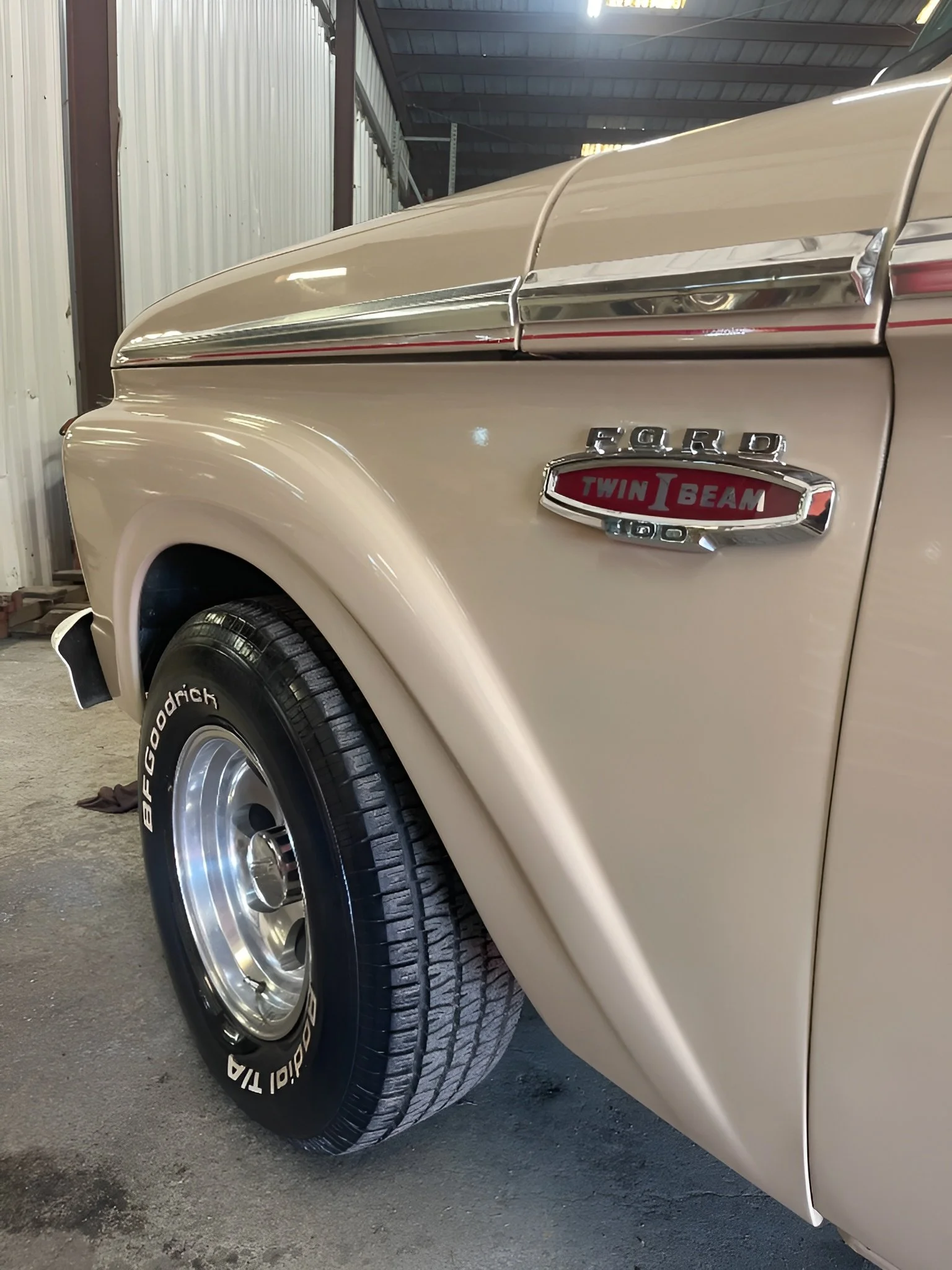 Close-up of a vintage beige Ford truck, showing the front wheel with BFGoodrich Radial T/A tires and a badge indicating it has a twin I-beam suspension.