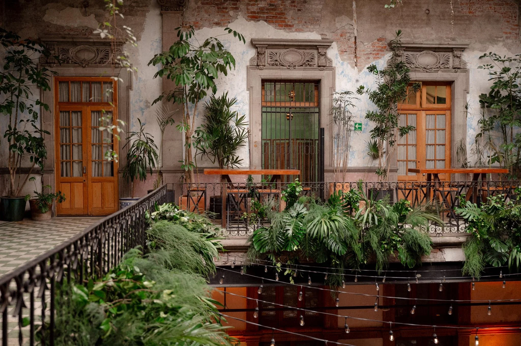 Historic courtyard at Proyectos Públicos General Prim in Mexico City featuring vintage architecture, tropical plants, wrought-iron balconies, and a romantic atmosphere ideal for weddings and events.