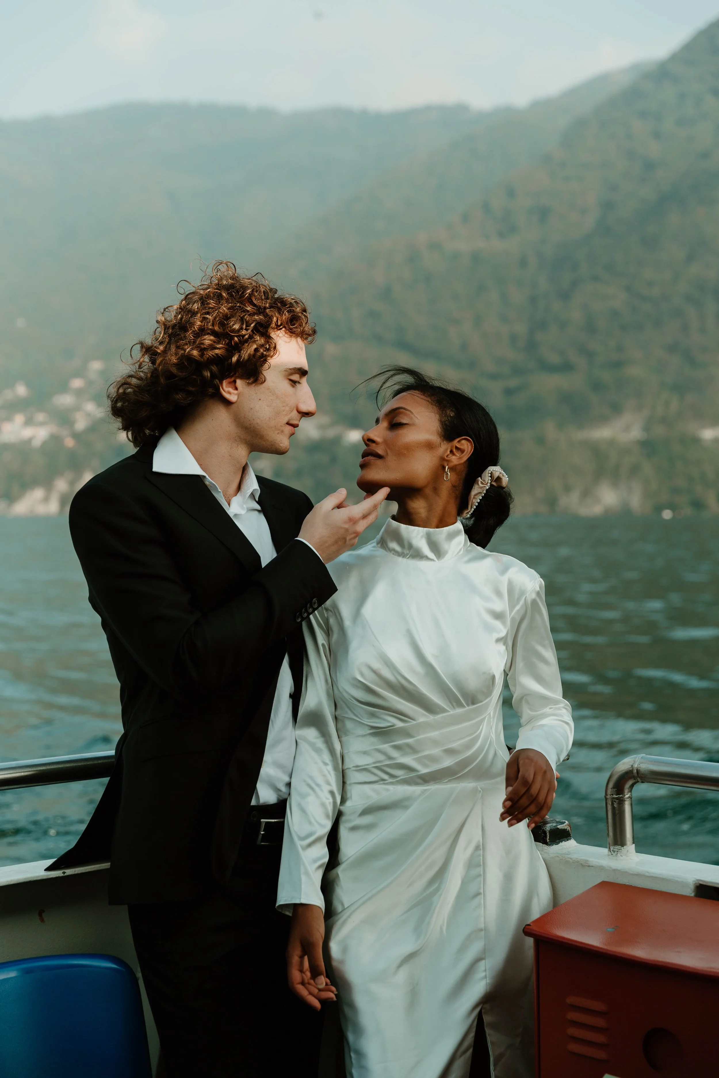 Bride and groom embracing on a ferry crossing Lake Como near Cernobbio, Italy