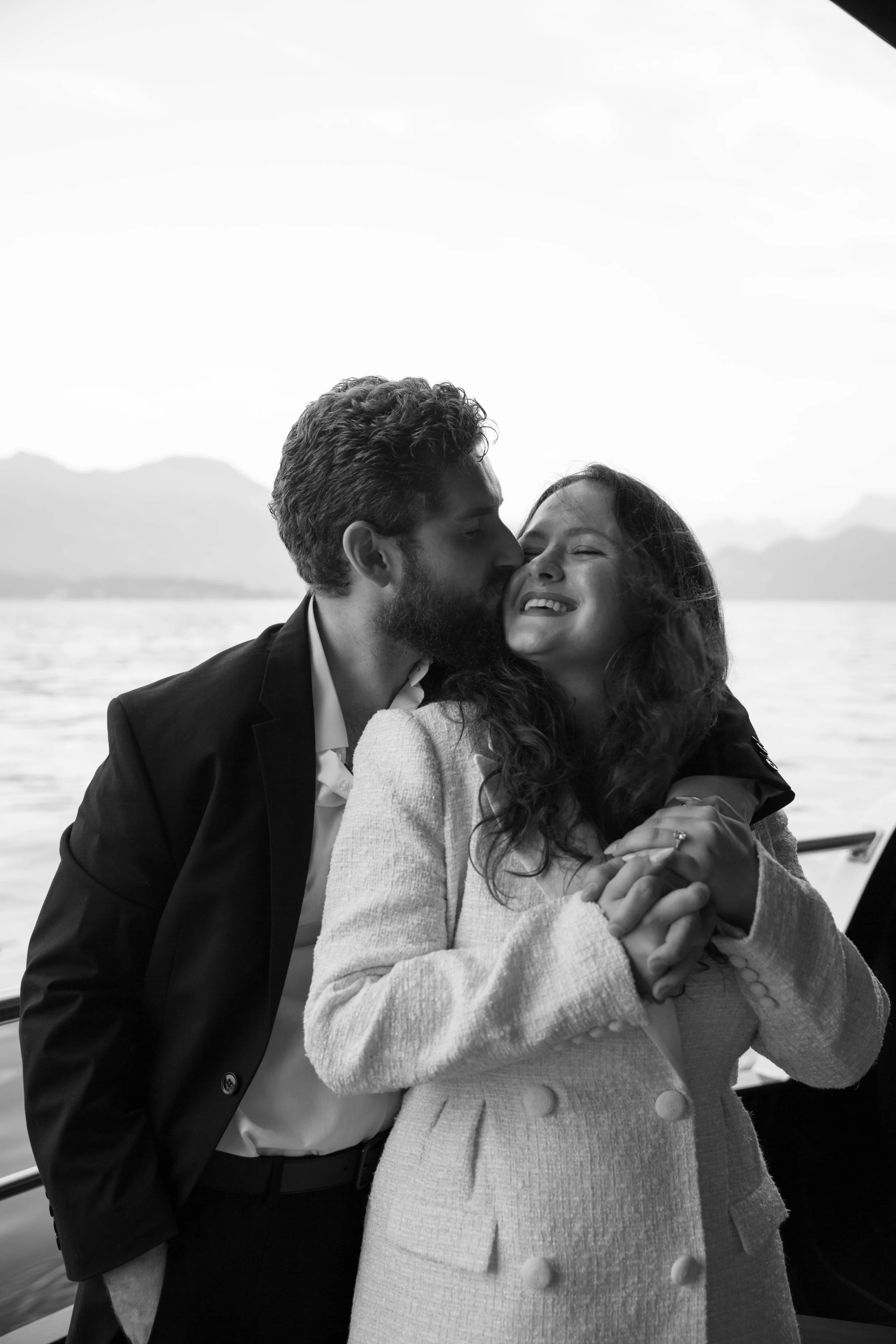 Black and white photo of a man kissing his fiancée on a boat during their Lucerne engagement session