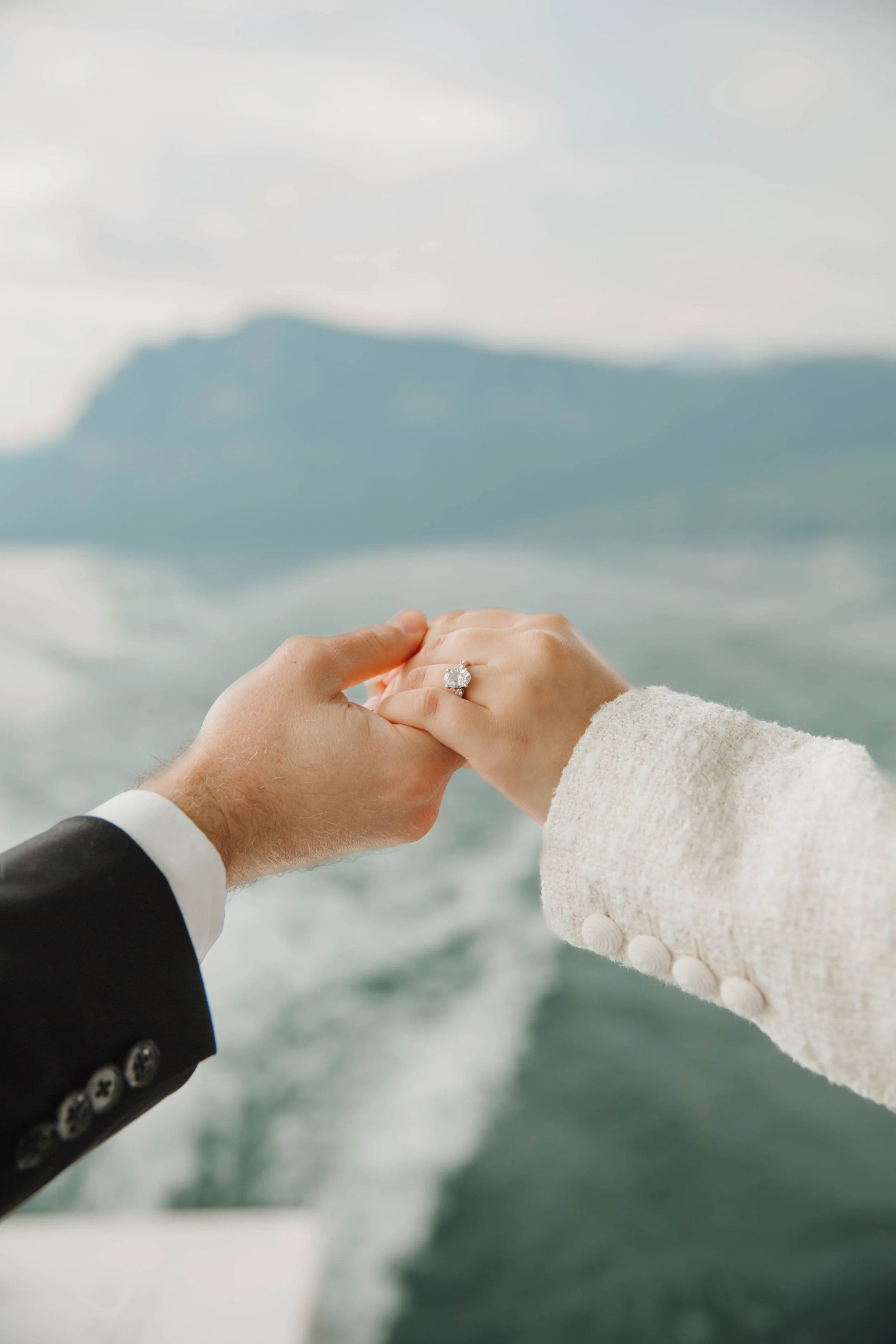 Close up of an engagement ring while the couple holds hands over the boat's wake on Lake Lucerne