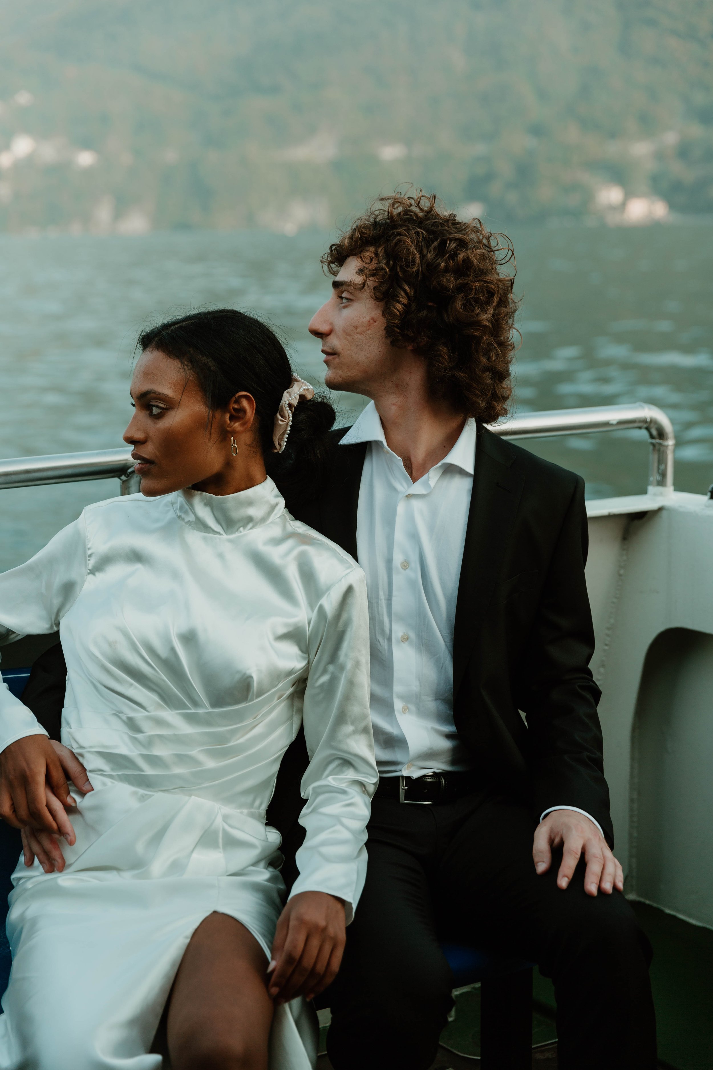 Couple in wedding attire seated together on the ferry deck crossing to Cernobbio